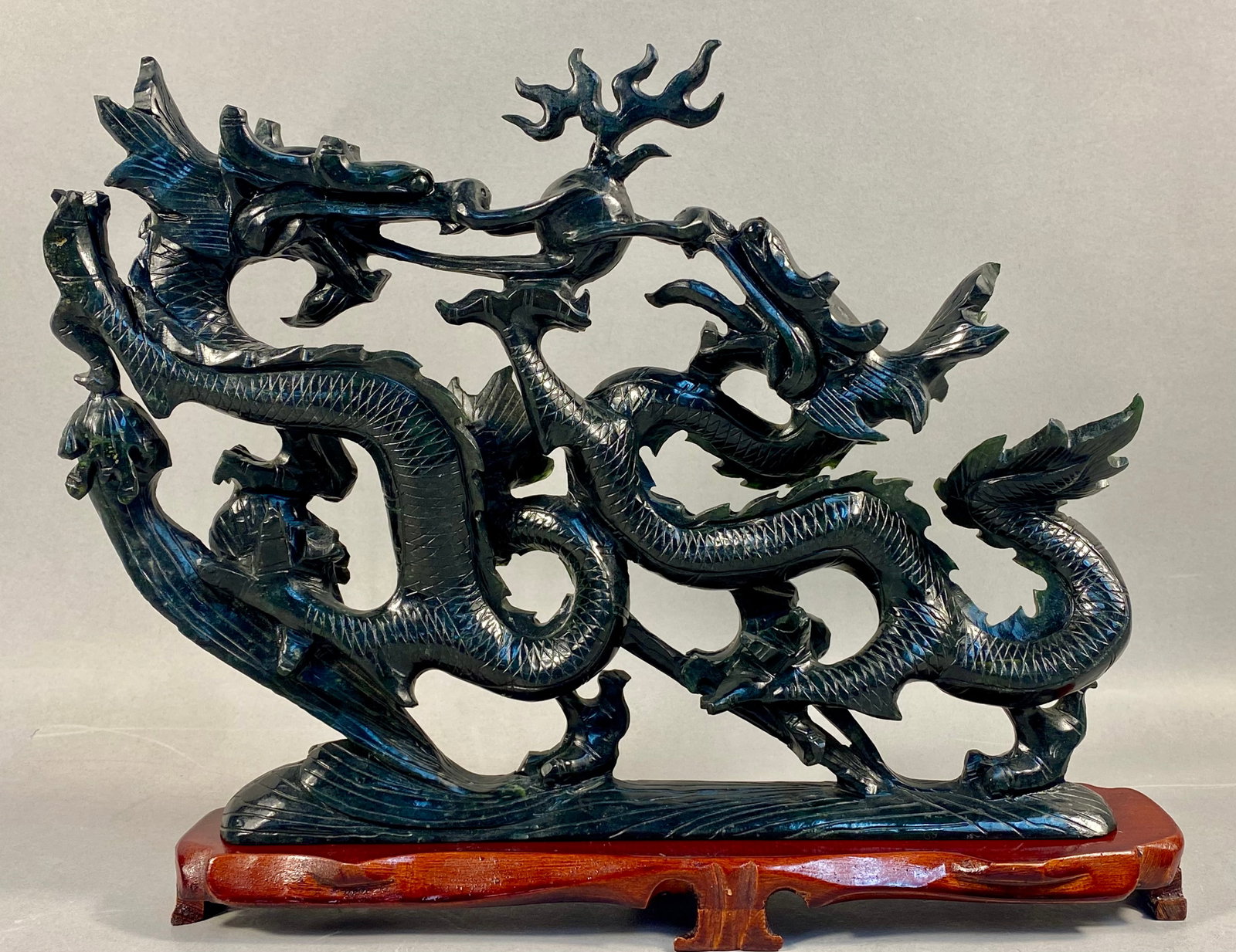 Large Chinese Carved Black Nephrite Jade Dragon Sculpture: This large carved sculpture is crafted from dark serpentine (bowenite), green to black nephrite jade or other hardstone simulants. The piece features an intricate openwork design depicting two
