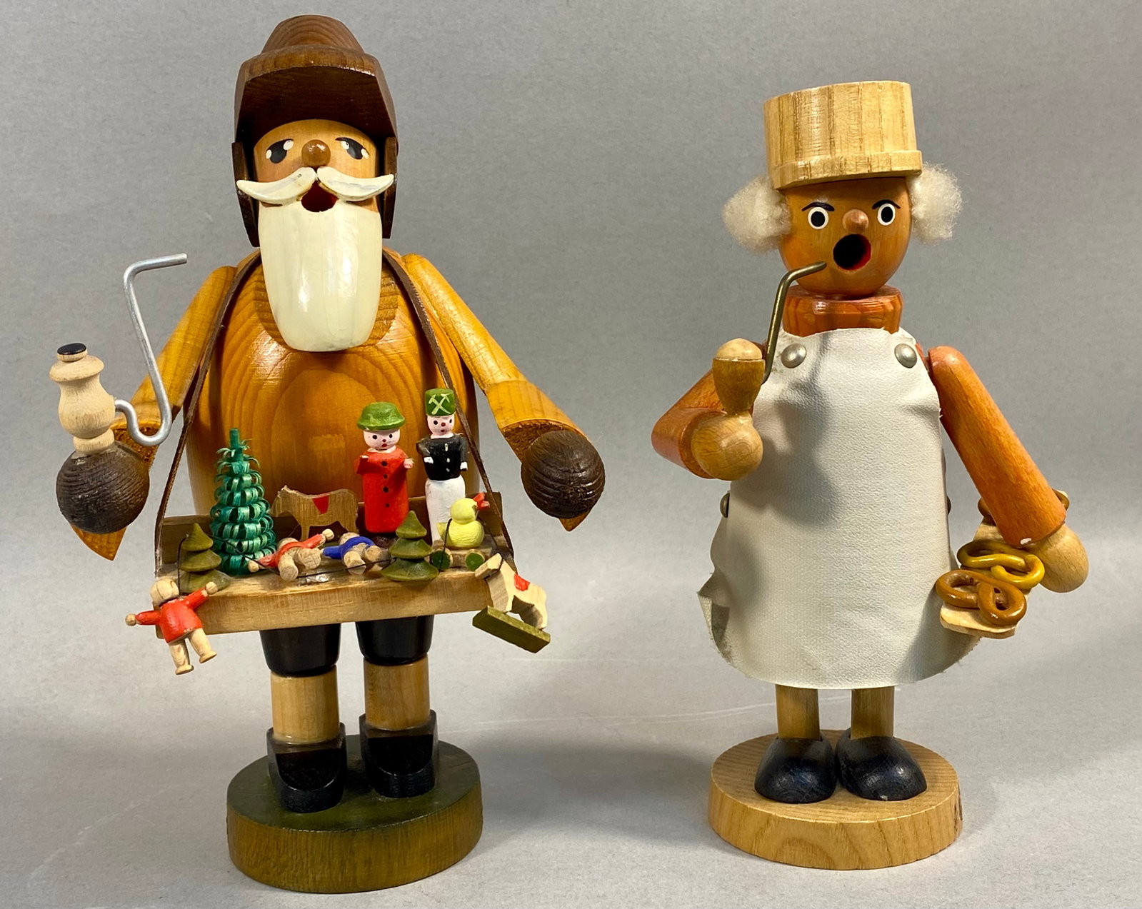 KWO Expertic Erzgebirge Wooden Incense Smokers: This pair of vintage German wooden incense smokers, traditionally known as Rauchermannchen, was manufactured by KWO in the Erzgebirge region. The set consists of two distinct figures: a toy seller