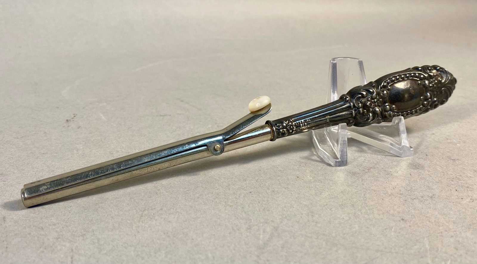 Antique Sterling Silver Repousse Handled Hair Curling Iron: This antique hair curling iron, also referred to as a Marcel iron, features an ornate sterling silver handle. The handle is decorated with elaborate floral and foliate repousse motifs, including