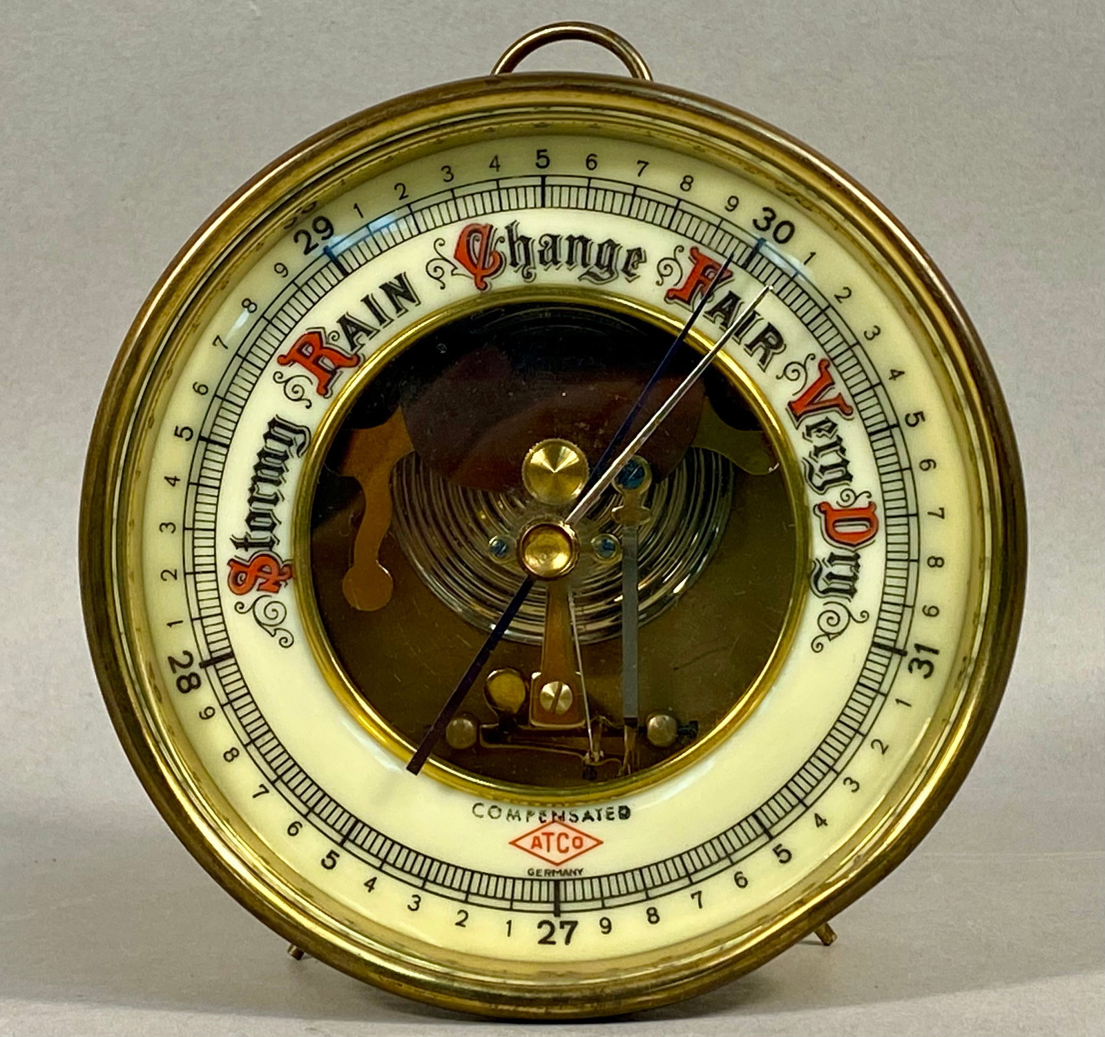 Vintage ATCO Germany Brass Aneroid Desk Barometer: A vintage circular aneroid desk barometer made in Germany for ATCO (American Thermo-Ware Co.). The instrument is housed in a polished brass case featuring an integrated top hanging ring and two small 