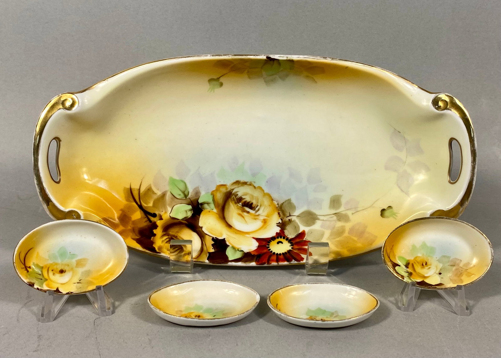 Five-Piece Hand-Painted Nippon Porcelain Relish Set: This five-piece porcelain set consists of a large, double-handled oval tray and four small individual oval dishes. Each piece is decorated with hand-painted floral motifs featuring yellow roses,