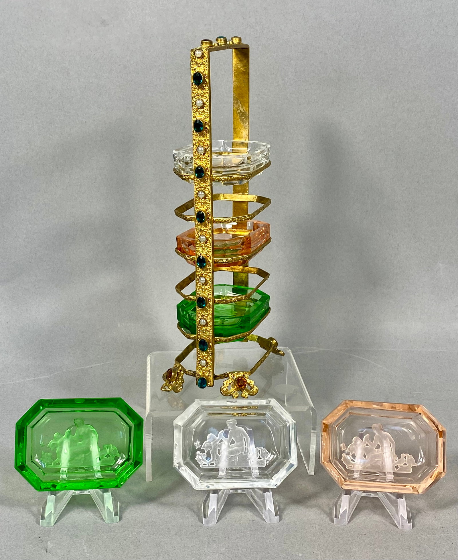 Six Bohemian Style Intaglio Glass Individual Dishes in Rack: A set of six octagonal glass individual dishes presented in a tiered carrying rack. The collection features pairs of dishes in three translucent colors: emerald green, clear, and a warm amber-peach