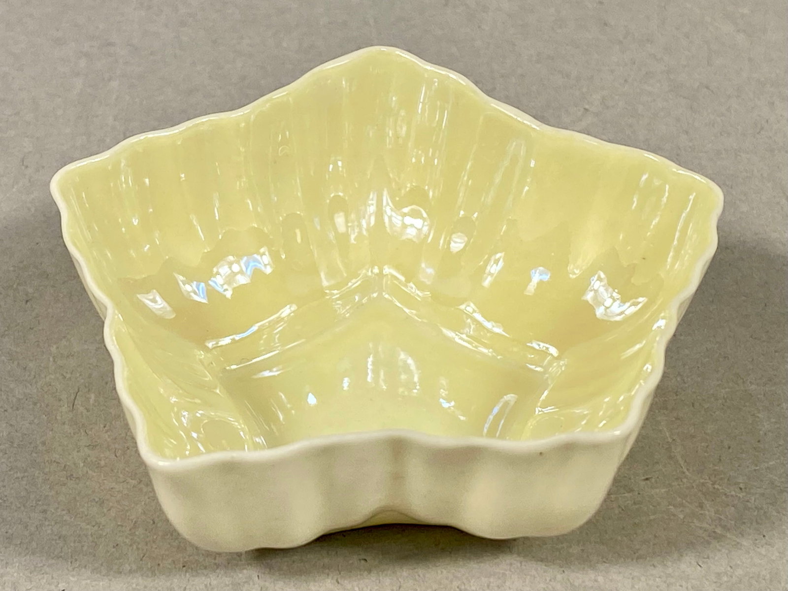 Belleek Parian Porcelain Star-Shaped Open Salt Cellar: A small parian porcelain vessel manufactured by Belleek Pottery in County Fermanagh, Ireland. This piece is designed in a five-lobed star shape with a fluted exterior body. The exterior features a