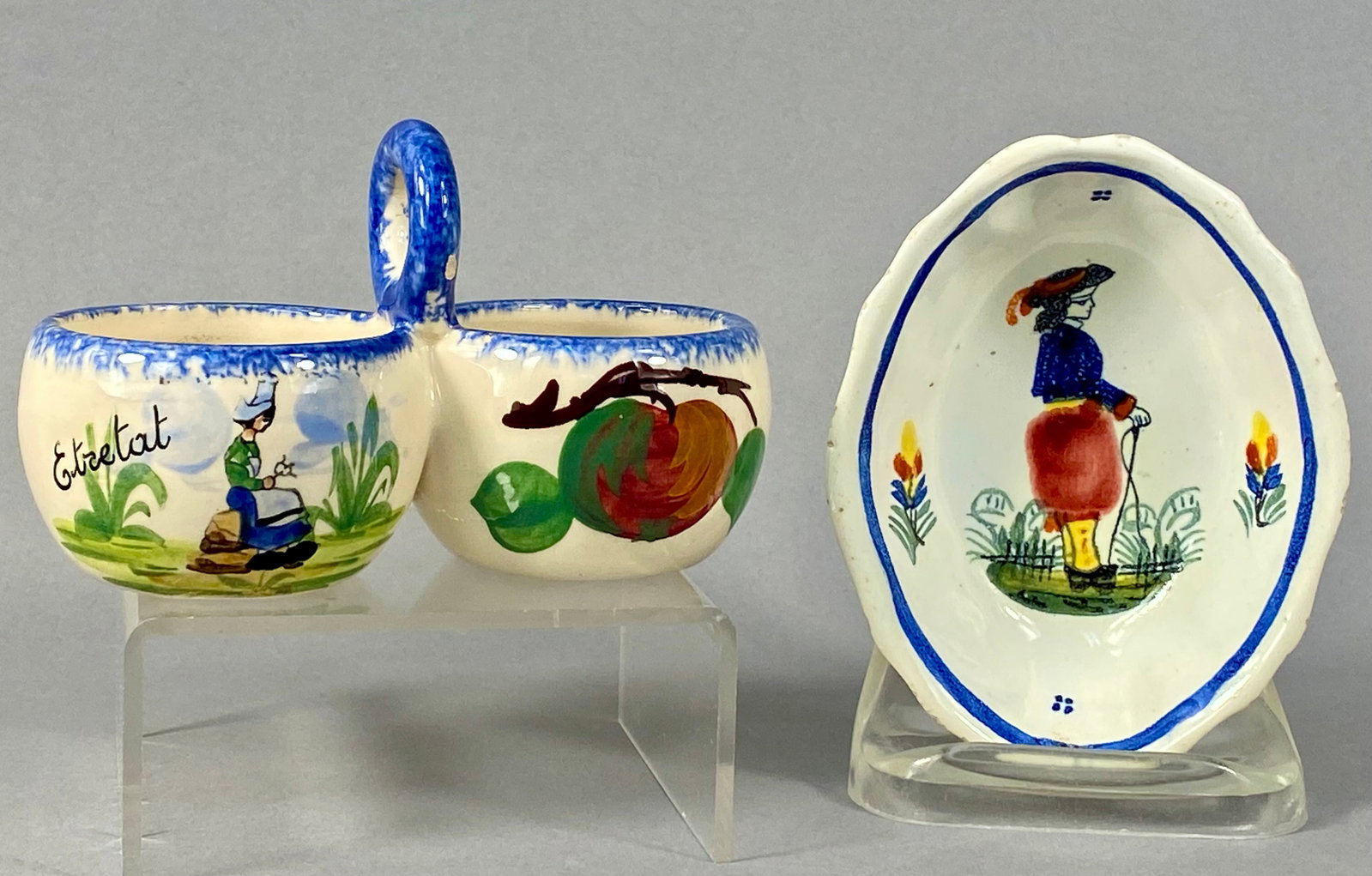 Two Pieces of French Quimper Faience Pottery: Two pieces of hand-painted French faience pottery from the Quimper region. The first item is a double salt cellar or condiment dish featuring two bowls joined by a central vertical loop handle. One bo