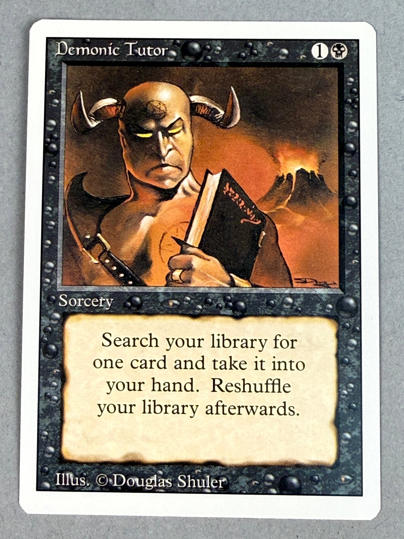 Magic The Gathering Demonic Tutor Revised: This is an individual Magic: The Gathering trading card for Demonic Tutor from the Revised Edition set. The card is a black sorcery featuring artwork by Douglas Shuler. It is identified as the
