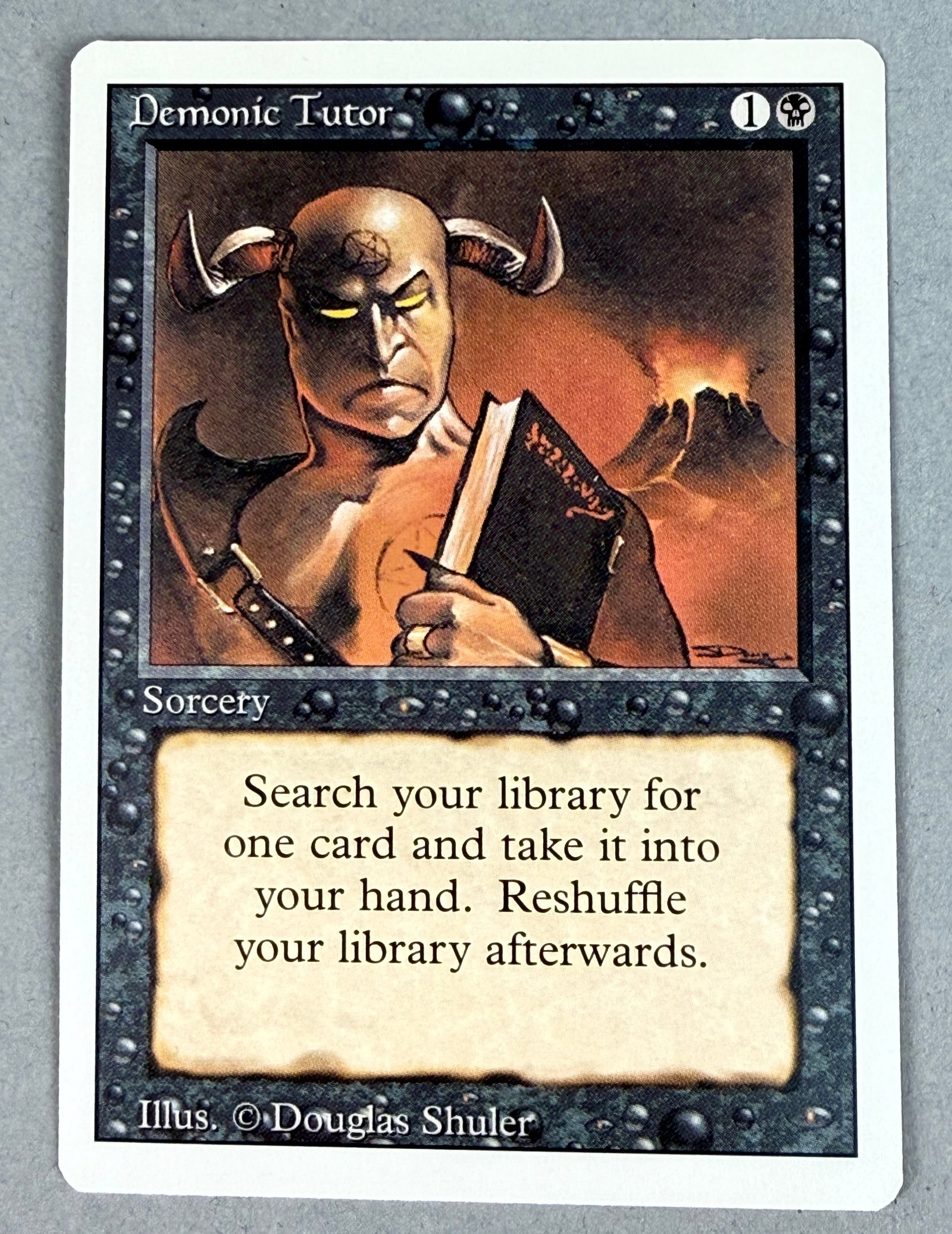 Magic The Gathering Demonic Tutor Revised: This is a single Magic: The Gathering trading card, Demonic Tutor, from the Revised Edition set. The card back features the standard Magic: The Gathering design with the five color orbs and the Deckma