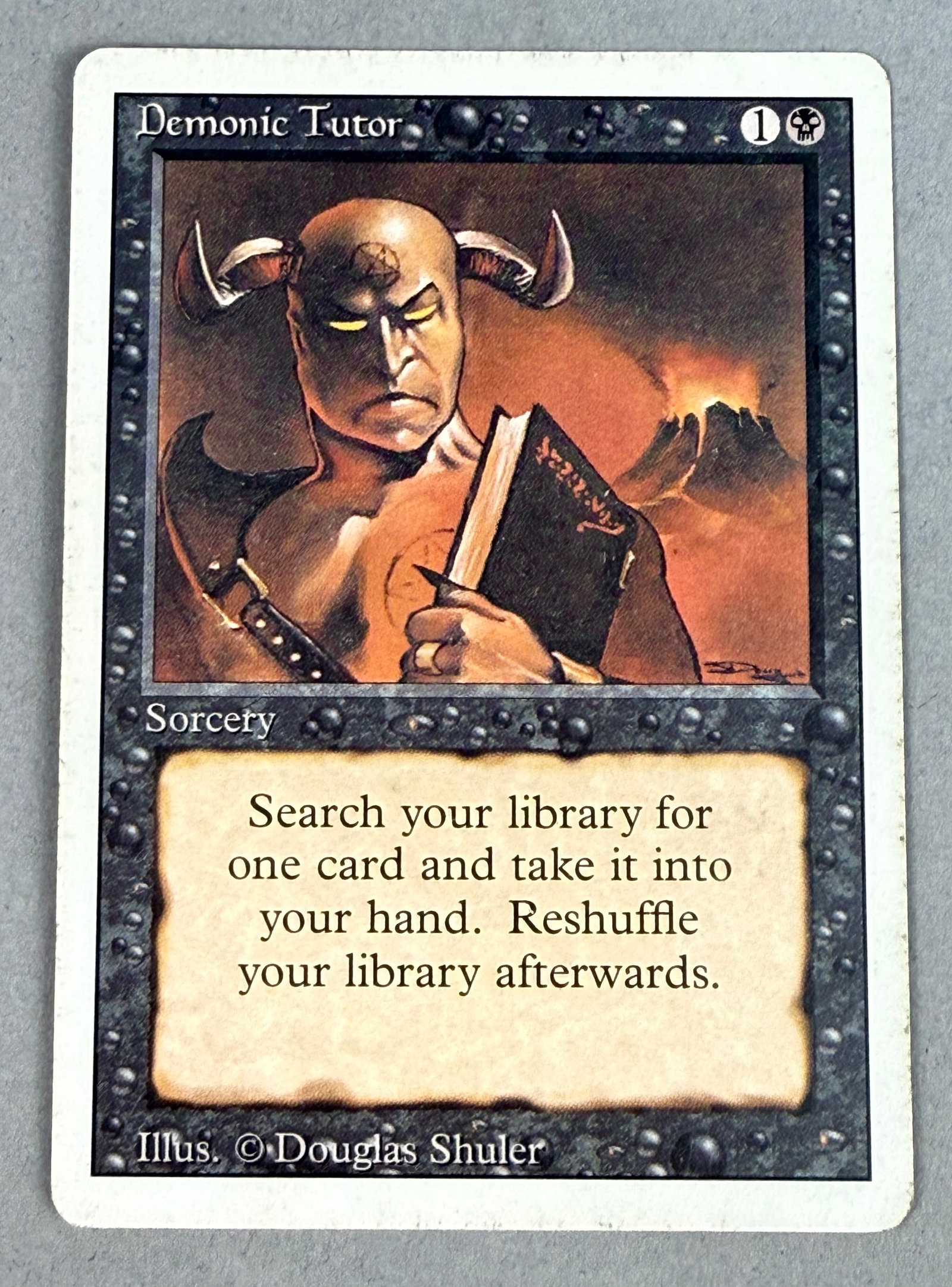Magic The Gathering Demonic Tutor Revised: This is a single Magic: The Gathering trading card, Demonic Tutor, from the Revised Edition. The reverse of the card features the standard five-color pentagon Magic: The Gathering card back with the D