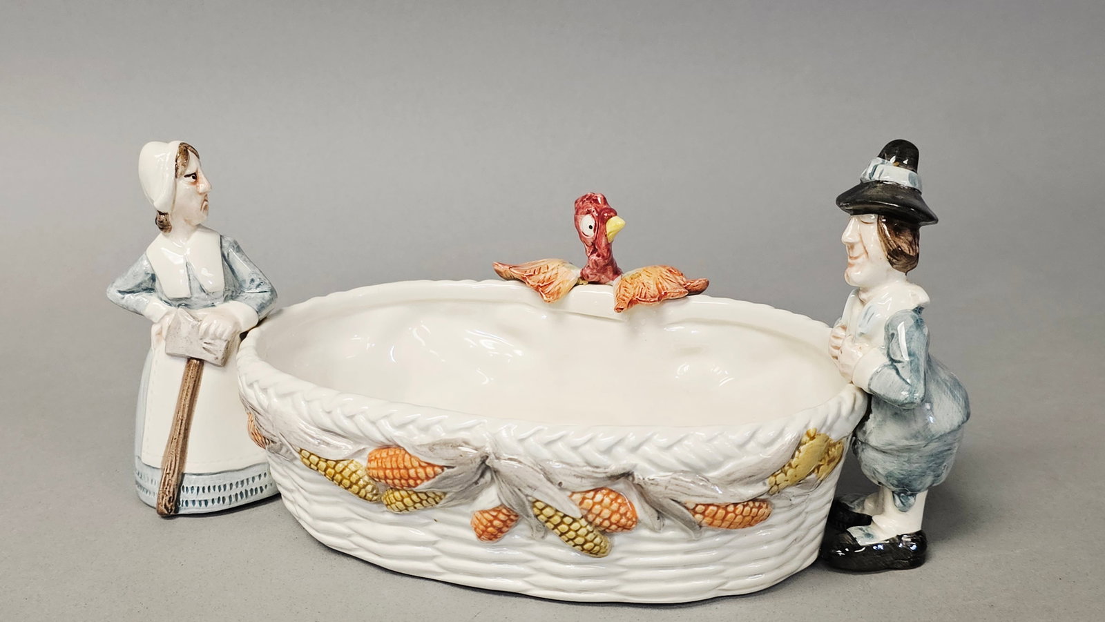 Fitz and Floyd Pilgrim's Progress Cranberry Server: A Fitz and Floyd glazed ceramic cranberry server from the Pilgrim's Progress holiday collection, dated 1990. The oval-shaped serving vessel features a cream-colored basket-weave textured body