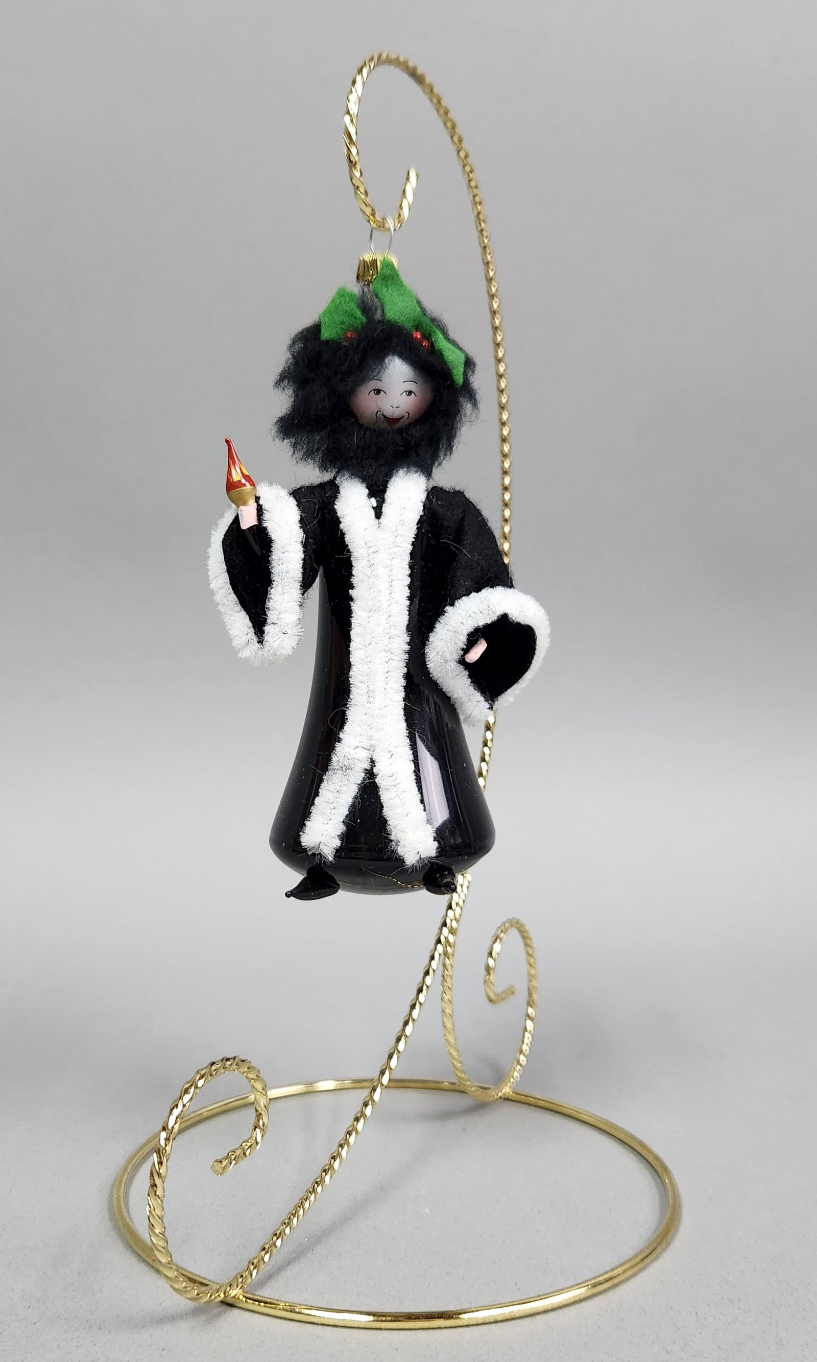 Italian Glass Robed Figure Ornament: Stand not included. Vintage black glass Christmas ornament depicting a robed figure with white pipe cleaner trim and a holly-adorned hat, featuring a gold-toned cap marked MADE IN ITALY. Very good