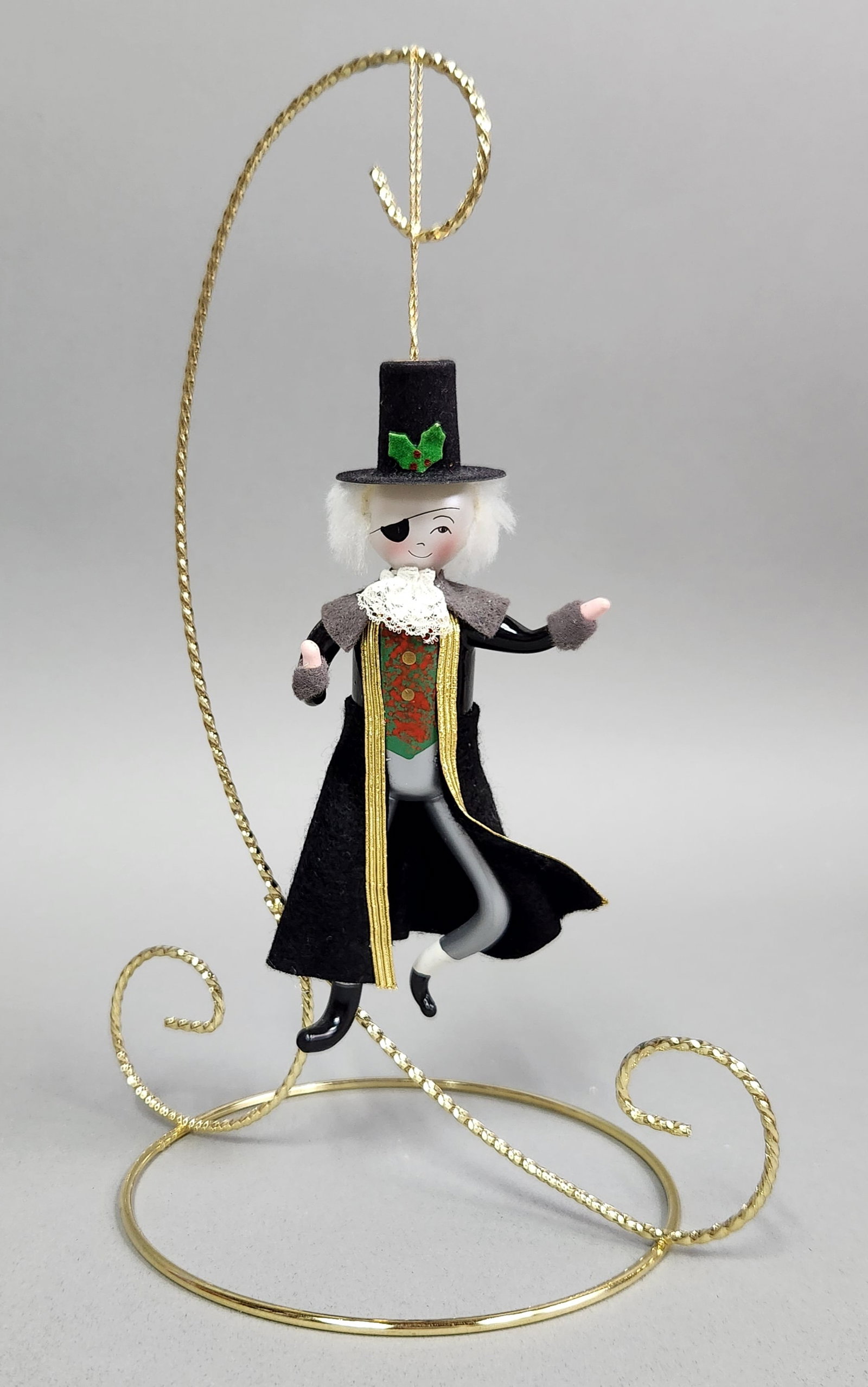 Italian Glass Ornament of a Gentleman: Stand not included. A vintage glass Christmas ornament of a gentleman with an eye patch and top hat, featuring black, gold, and white finishes with red and green accents, measuring approximately 5.5