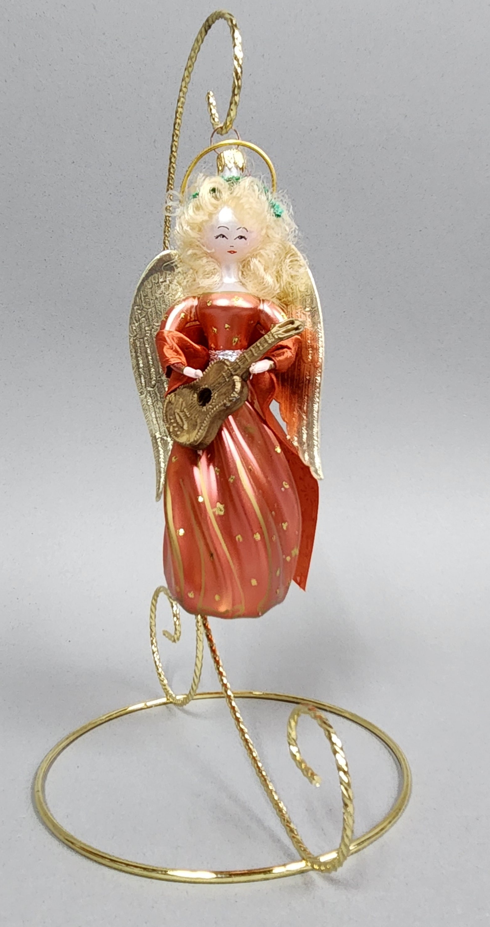 Italian Glass Angel Ornament: Stand not included. A vintage Italian blown glass angel ornament with a red metallic finish and blonde hair, presented on a gold-tone metal stand measuring approximately 7 inches tall. Very good condi
