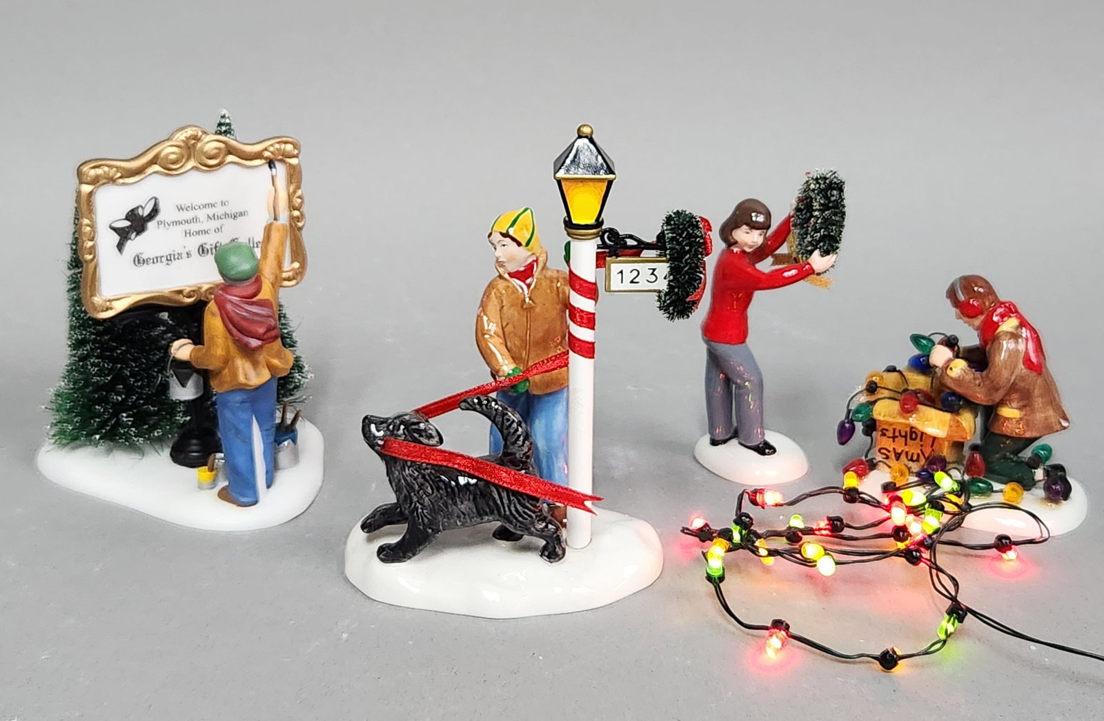Dept 56 Holiday Village Accessories: The collection includes several sets such as Painting Our Own Village Sign, More Decorations? (item #56.55231), Asleep At The Bus Stop (item #56.58993). Also included is a set of 25 mini LED Village