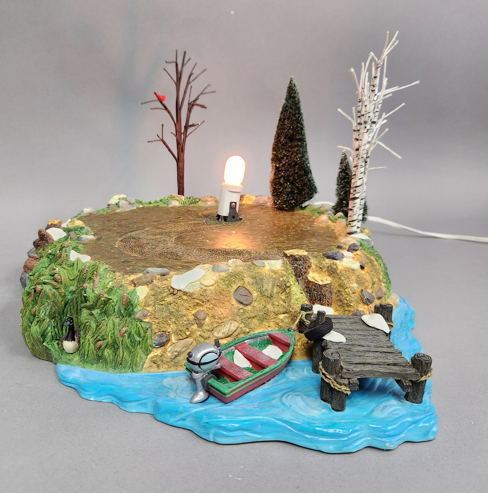 Dept 56 Sounds of the North Woods: A Department 56 Sounds of the North Woods lighted village landscape accessory featuring a dock, rowboat, and various trees, measuring approximately 12.5 by 11 inches. Both the sounds and light work. V