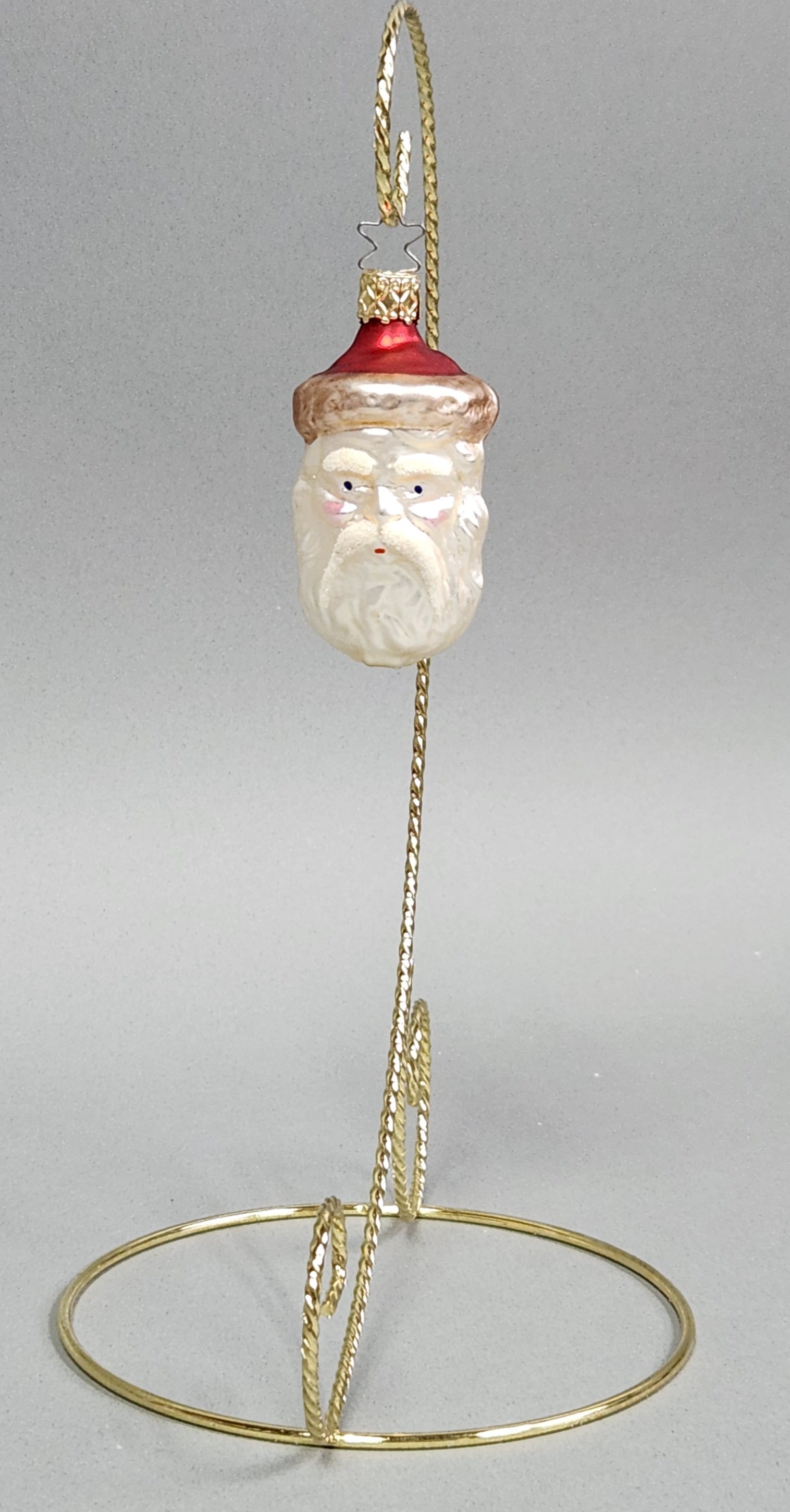 Inge-Glas Santa Claus Ornament: Stand not included. An Inge-Glas hand-painted, blown glass Christmas ornament depicting the head of Santa Claus. Stamped MADE IN GERMANY and features the manufacturer signature star-shaped wire