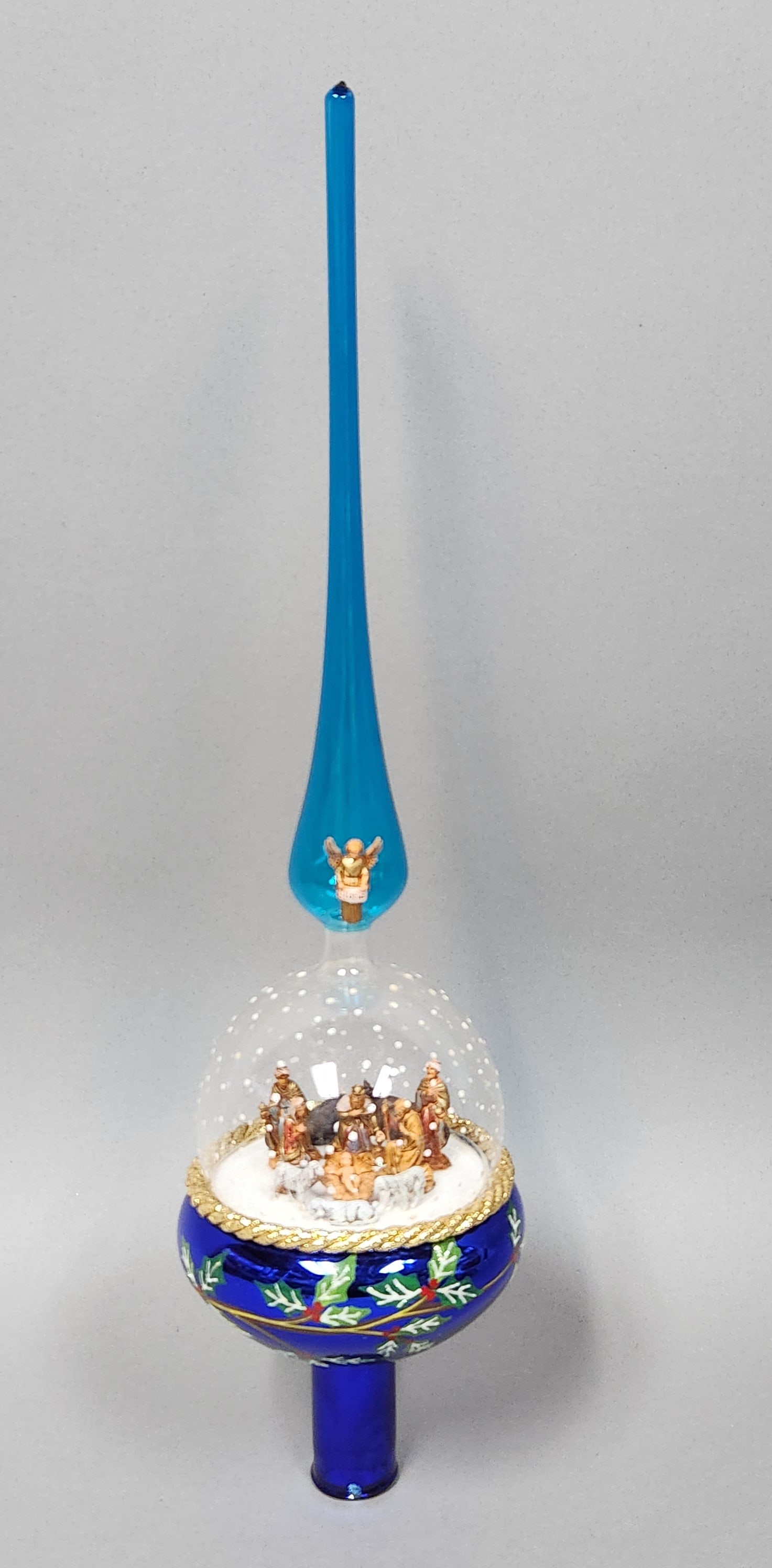 Christopher Radko Nativity Tree Topper: Christopher Radko hand-blown glass Christmas tree finial features a multi-tiered design with religious iconography. Overall Length: Approximately 18 inches.The glass finial appears to be in good condi