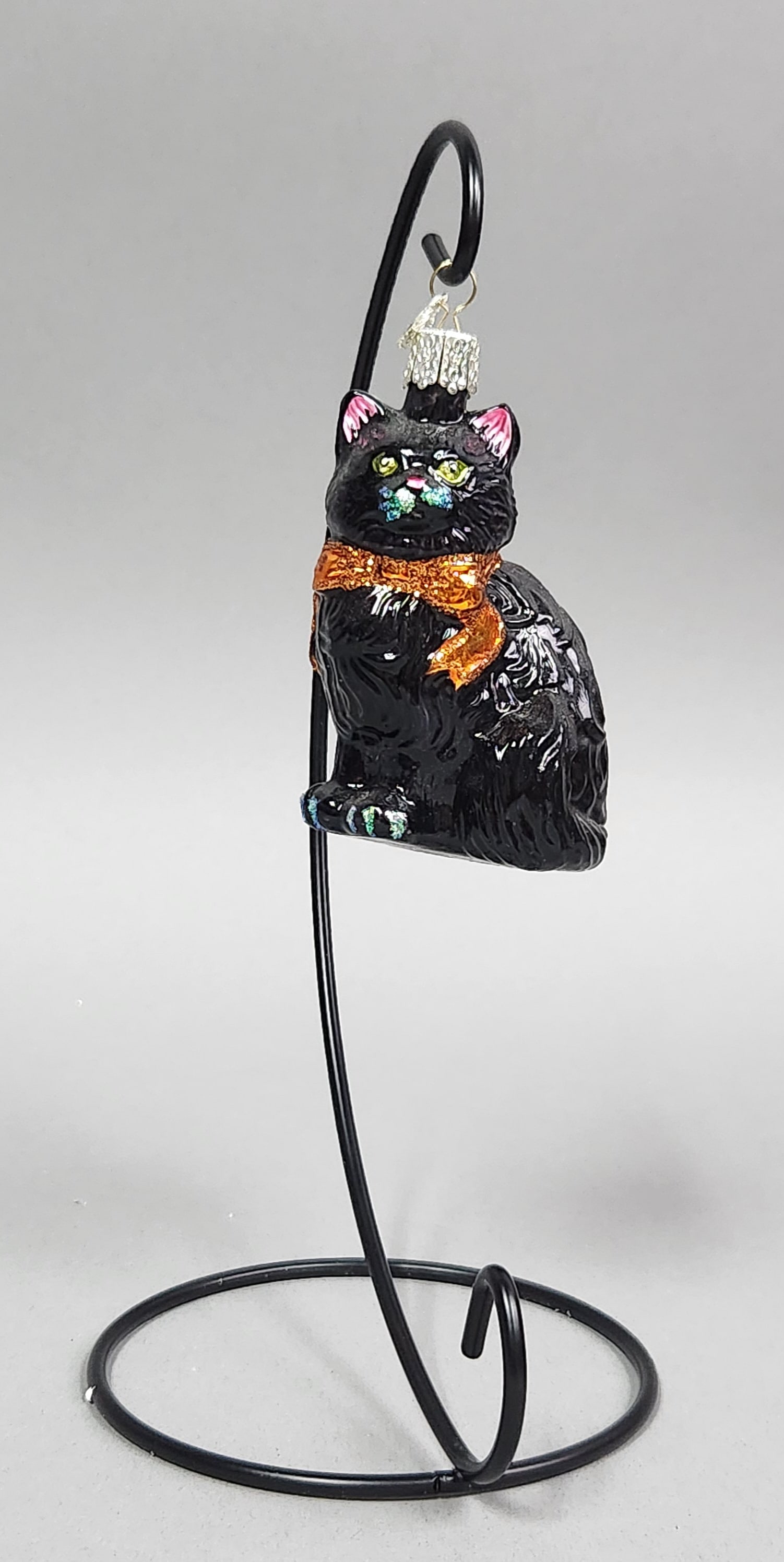 OWC Black Long Haired Cat Glass Ornament: Stand not included. An Old World Christmas black long-haired cat blown glass Christmas ornament featuring an orange glitter bow and an OWC heart charm, measuring approximately 3.5 inches in height.