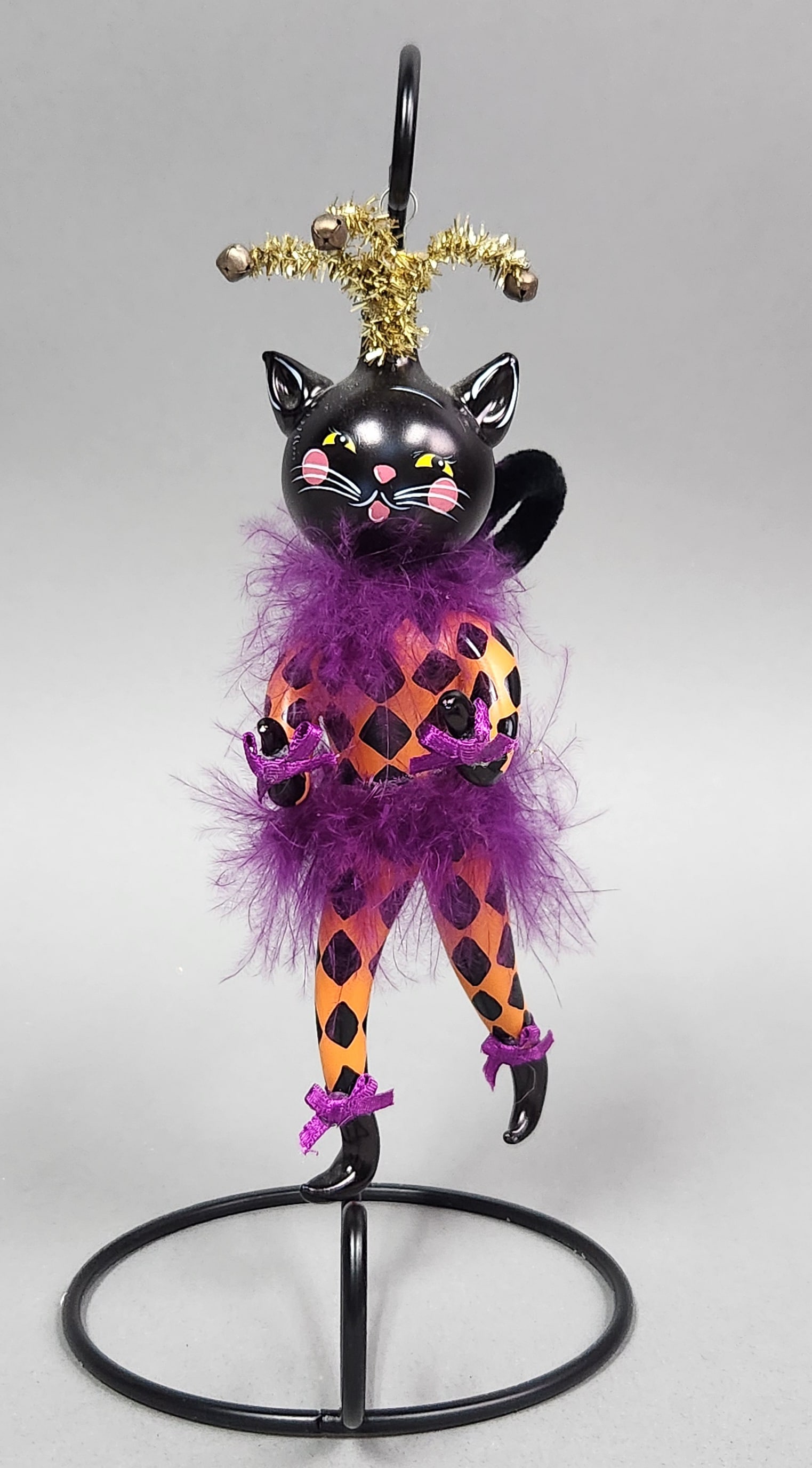 Harlequin Black Cat Ornament: Stand not included. A decorative plastic black cat figurine presented in a harlequin-inspired style. Length: Approximately 7 inches. The item appears to be in good condition. Painted surfaces are