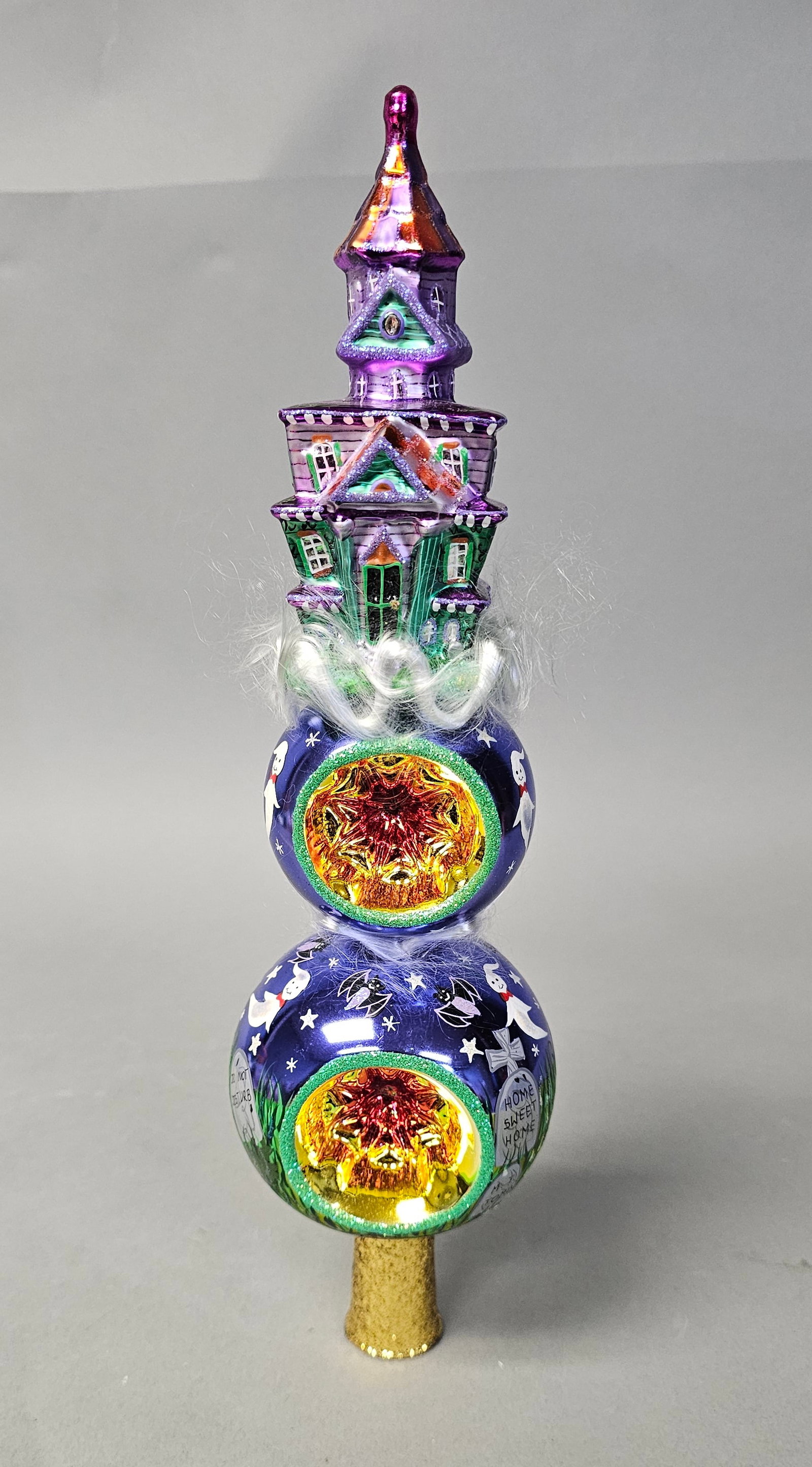 Radko Haunted Heights Halloween Tree Topper Finial: This Christopher Radko Haunted Heights Finial is a hand-blown and hand-painted glass holiday tree topper manufactured in Poland. The piece features a three-tier vertical design. A manufacturer label o