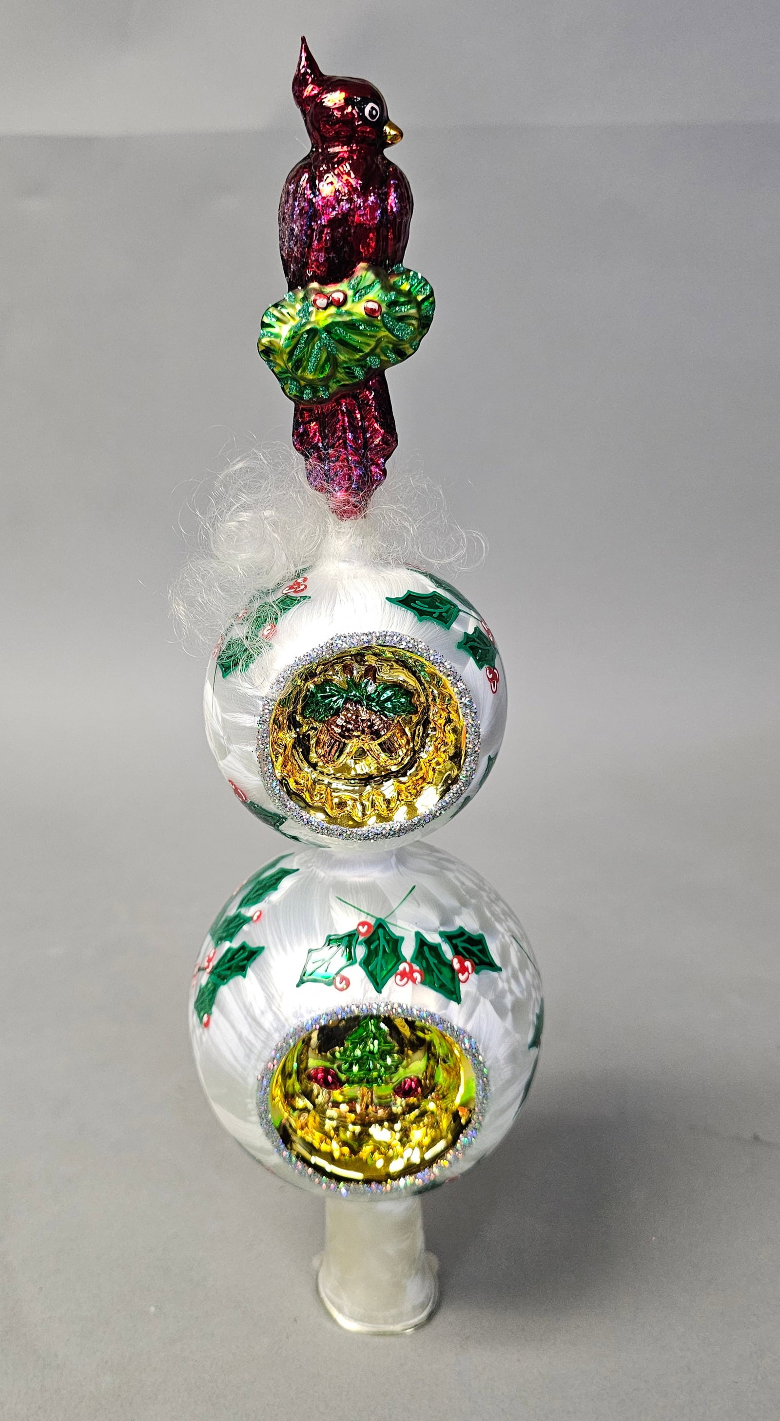 Radko Cardinal Rules Christmas Tree Topper Finial: A hand-blown and hand-painted glass Christmas tree topper finial by Christopher Radko, titled Cardinal Rules. This three-tier ornament is crafted in Poland and features a vibrant red cardinal bird at 