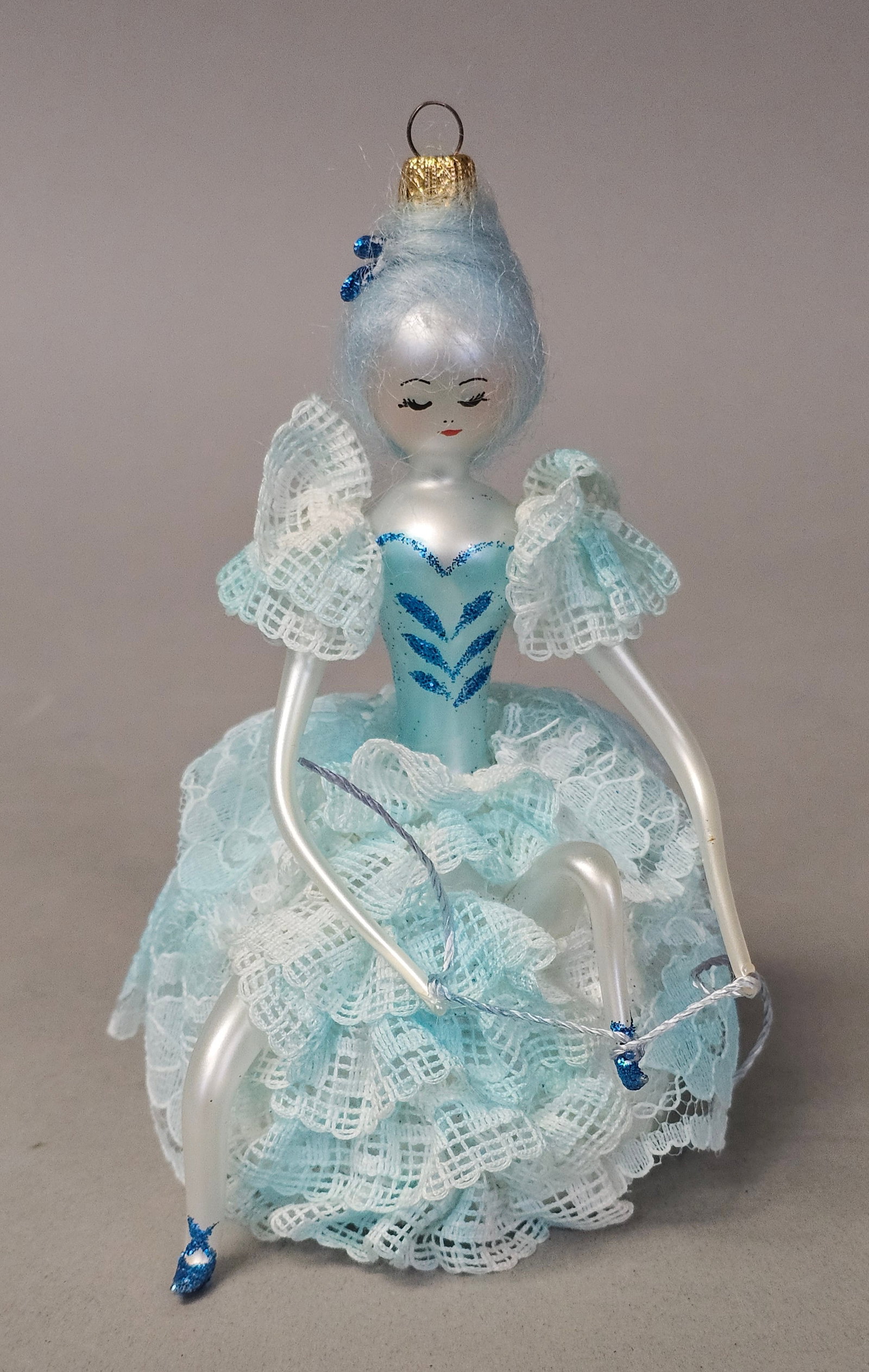 Italian Hand Blown Glass Woman Ornament: This Italian hand-blown silvered glass Christmas ornament depicts a seated lady in an elaborate lace gown. The gold-tone metal hanging cap is stamped with MADE ITALY. Height: 5.5 inches. The ornament 