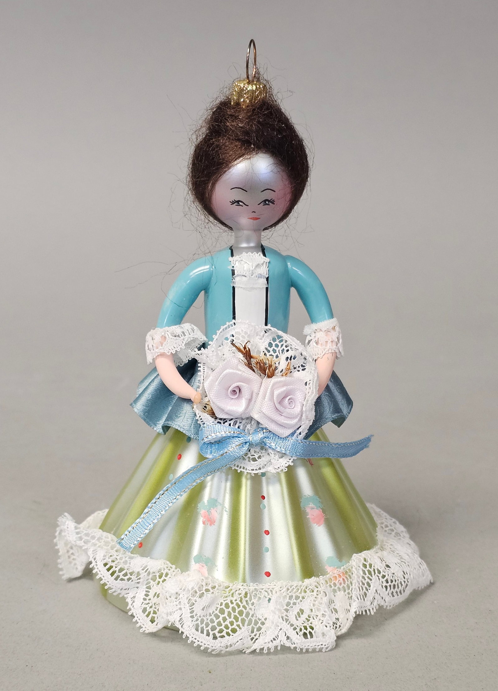 Italian Hand Blown Glass Woman Ornament: This vintage blown glass Christmas ornament depicts a woman in period-style dress. The gold-tone metal ornament cap features stamped lettering that reads MADE ITALY. Height: 5.5 inches. The ornament i