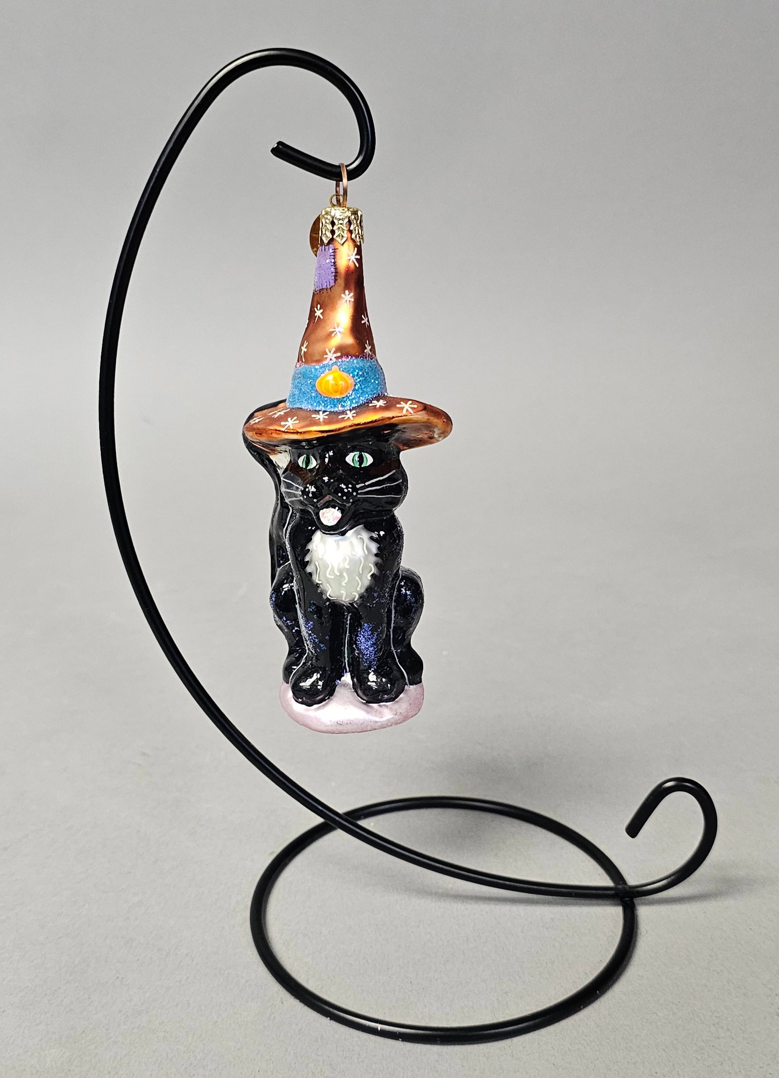 Radko Frisky Business Halloween Glass Cat Ornament: *STAND NOT INCLUDED* This hand-crafted glass ornament is a Christopher Radko design titled Frisky Business, originally released in 1999. The piece features a seated black cat with green eyes, white wh