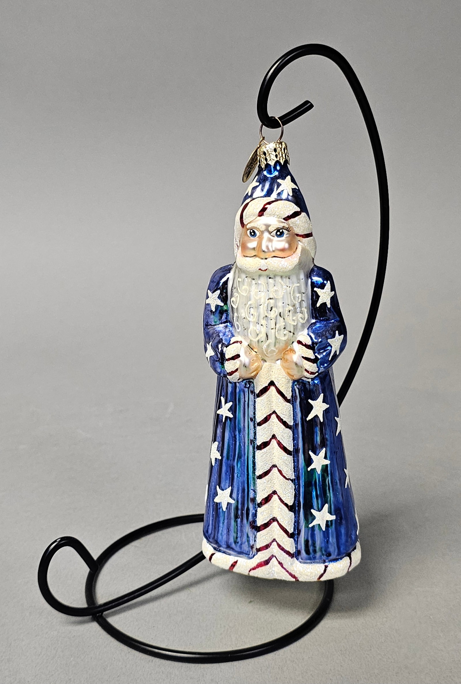 Radko Patriotic Santa Glass Christmas Ornament: *STAND NOT INCLUDED* This glass Christmas ornament by Christopher Radko depicts a standing Santa Claus designed with a patriotic theme. Height: 6 inches. The ornament is in good condition with no chip