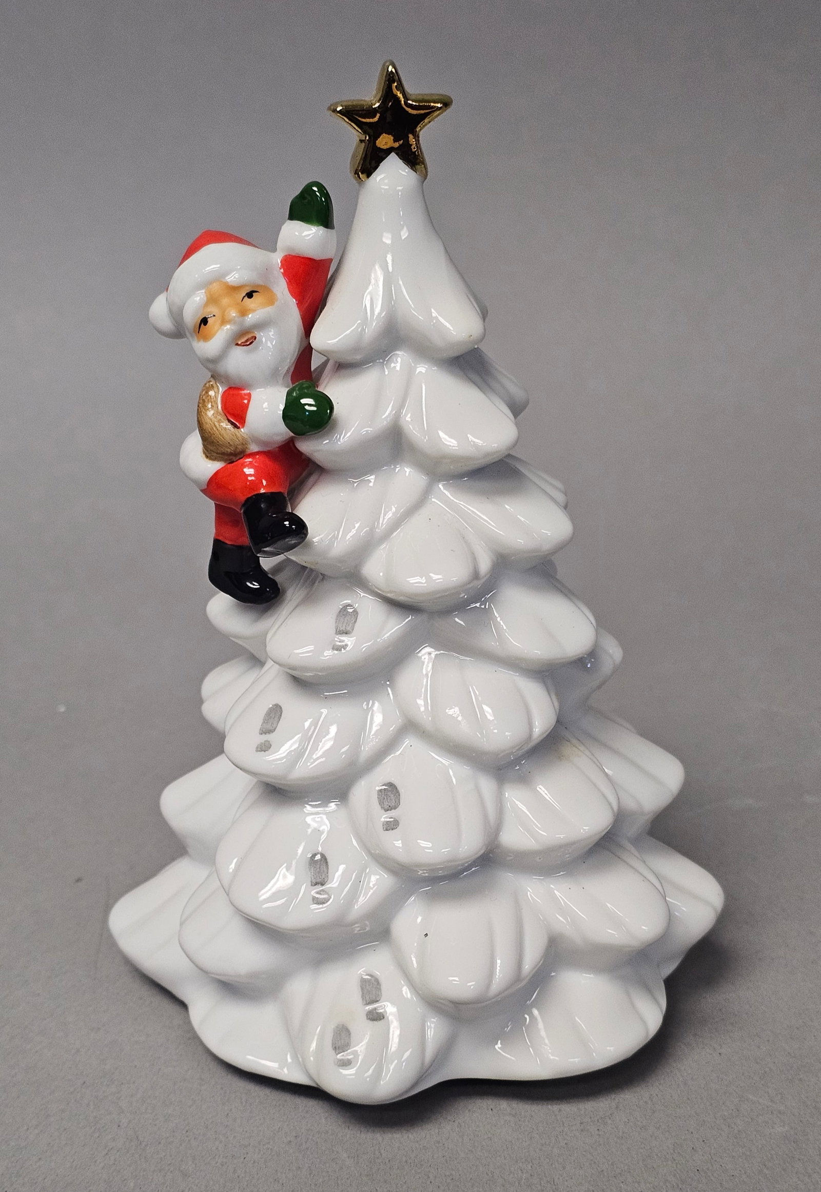 Vintage Japanese Porcelain Tree Music: A vintage glazed porcelain musical figurine featuring a stylized white tiered Christmas tree topped with a five-pointed metallic gold star. consists of a circular wooden base plate housing an integrat