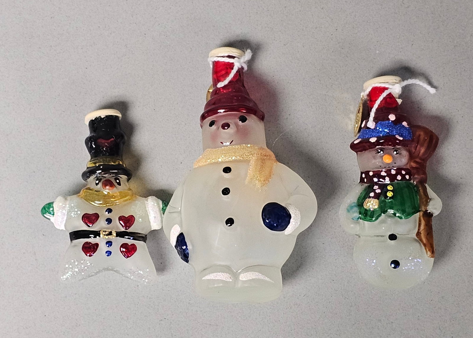 Christopher Radko Glass Snowman Light Covers: A trio of hand-painted, mouth-blown glass Christmas light covers produced by Christopher Radko. The collection includes three distinct whimsical snowman designs. Two of the ornaments are accompanied b
