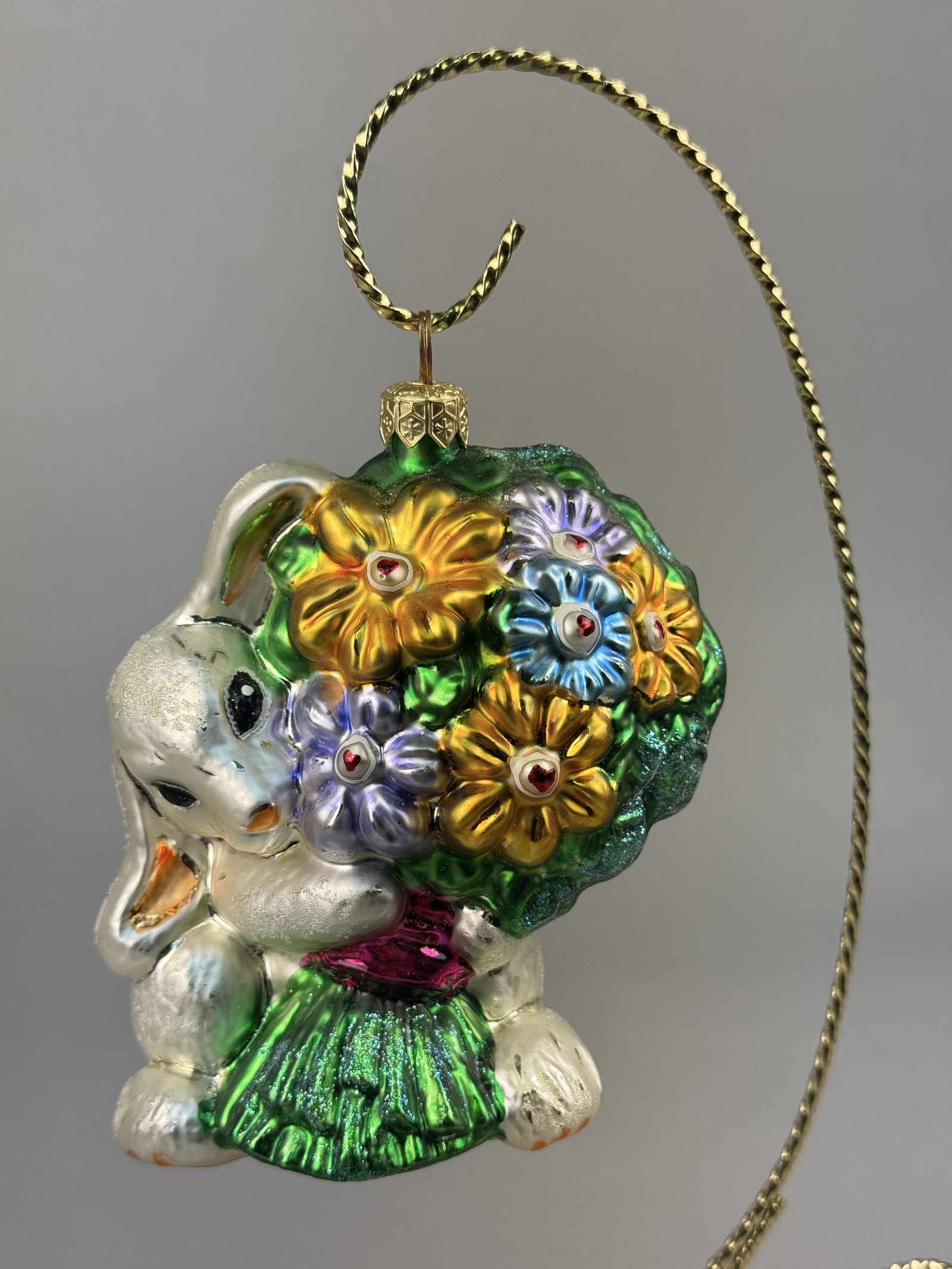Radko Glass Bunny Ornament You're the Best Mom: Stand not included. A Christopher Radko mouth-blown glass ornament featuring a pearlescent white bunny rabbit holding an oversized bouquet of metallic flowers in gold, blue, and purple. The ornament i