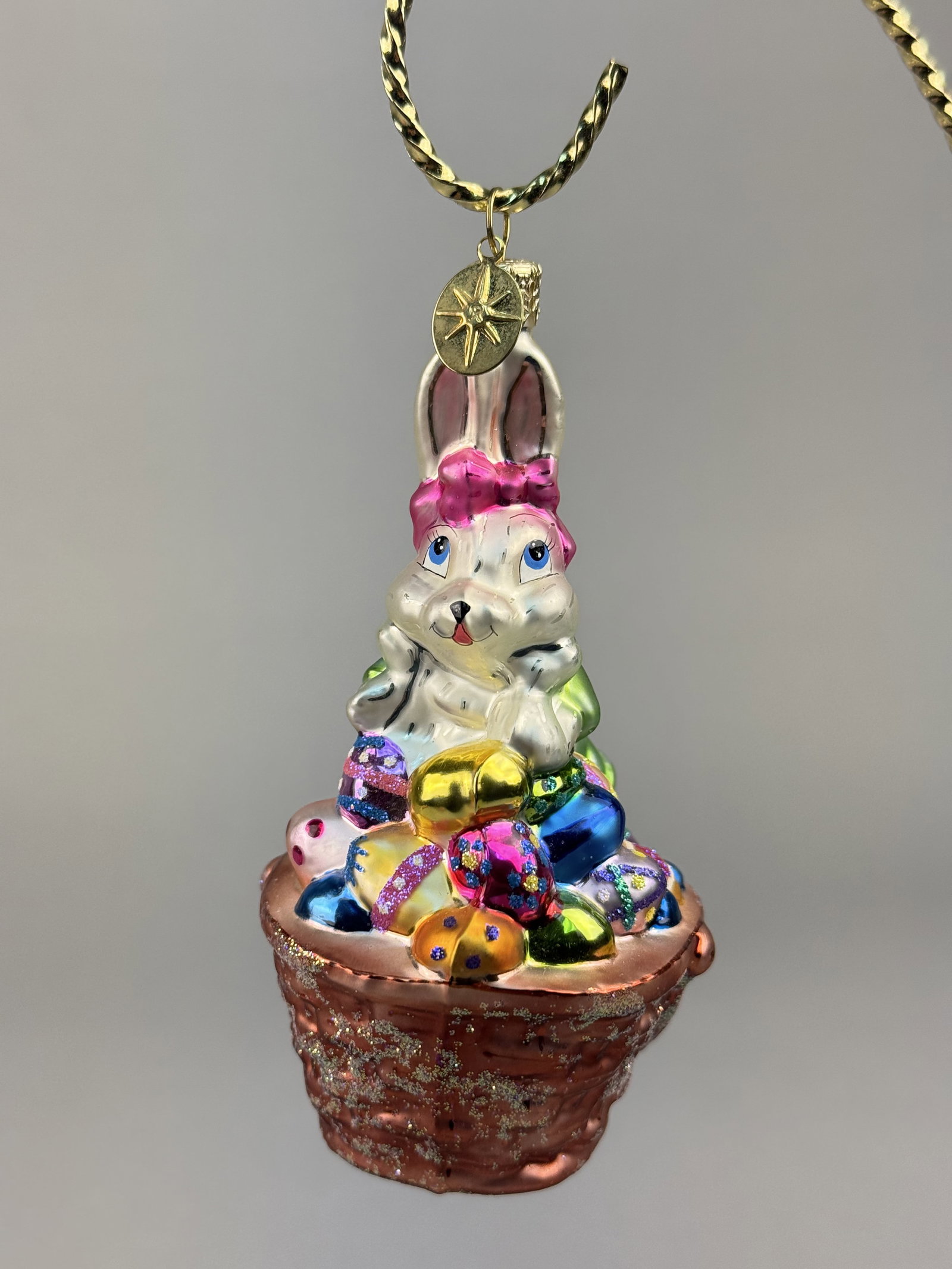 Christopher Radko Hoppy Easter Hand-Blown Glass Bunny in Basket Ornament: Stand not included. This hand-blown glass holiday ornament is identified as the Hoppy Easter model by Christopher Radko. The ornament features a gold-toned decorative metal cap and hanging loop. Attac