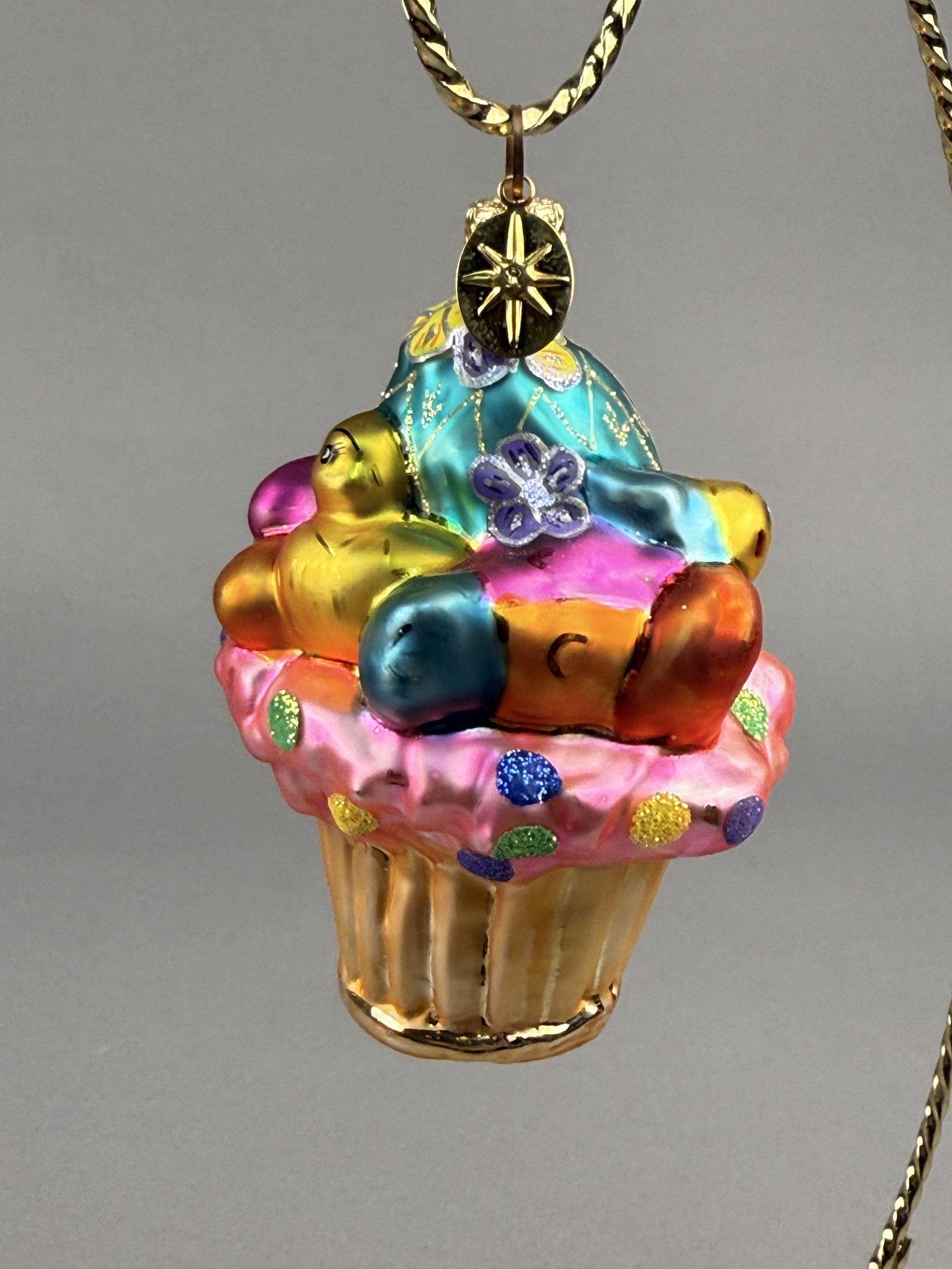 Radko Bakery Tweets Easter Cupcake Glass Ornament: Stand not included. This hand-blown silvered glass ornament by Christopher Radko is titled Bakery Tweets and features an Easter-themed cupcake design. The ornament is finished with a scalloped gold-to