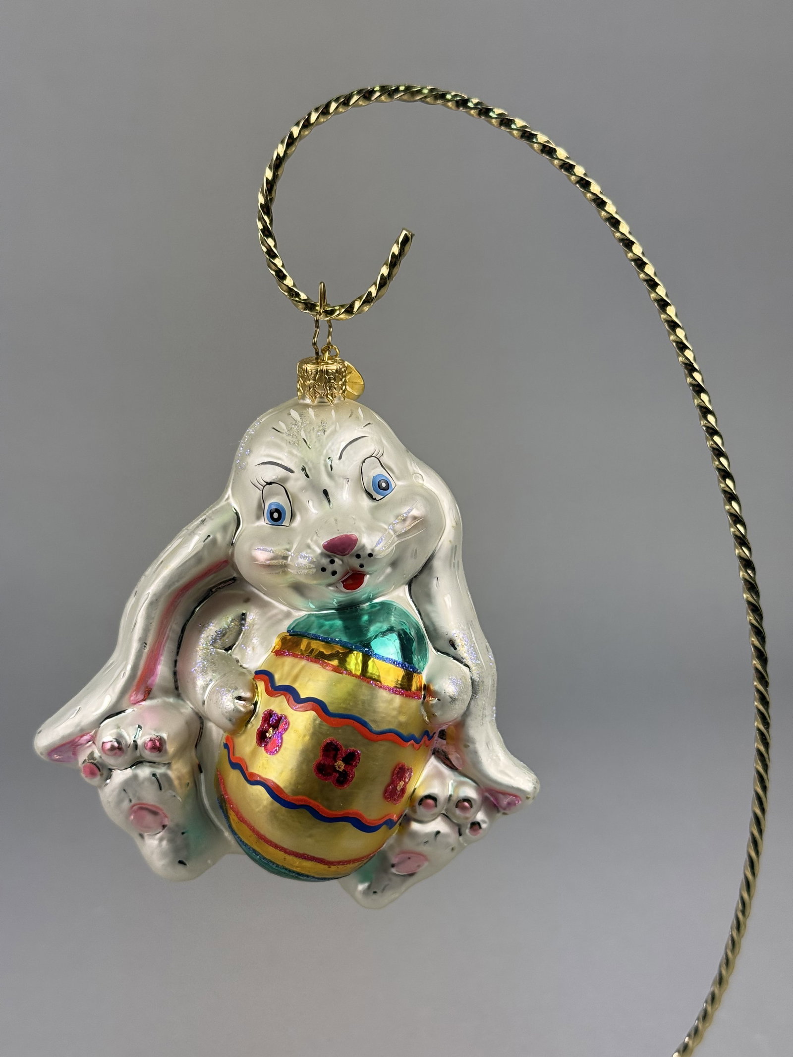 Christopher Radko Blown Glass Easter Bunny with Egg Ornament: Stand not included. This mouth-blown glass holiday ornament is produced by Christopher Radko. The ornament is topped with a gold-toned metal crown cap and a signature Christopher Radko oval metal char