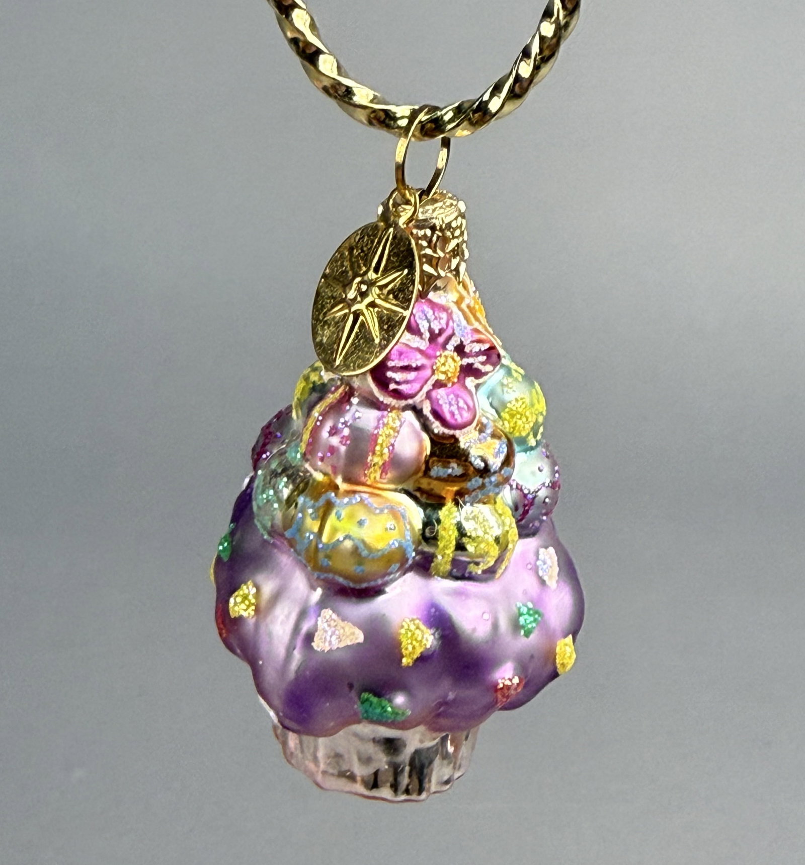 Radko Hand-Painted Glass Easter Egg Cupcake Ornament: Stand not included. This mouth-blown, hand-painted glass ornament by Christopher Radko is designed in the form of a whimsical tiered dessert or Easter cupcake. The ornament is fitted with a gold-tone