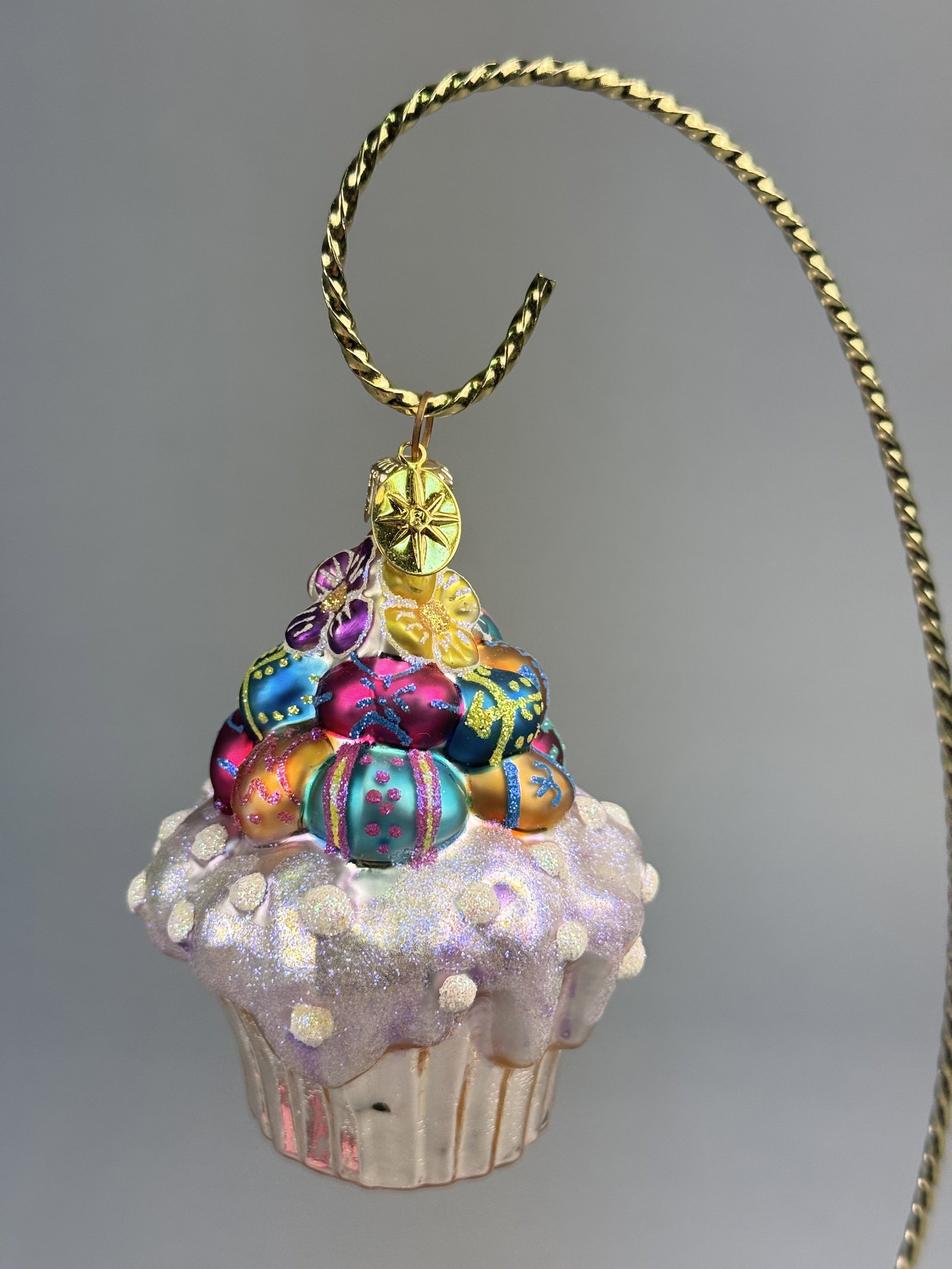 Radko Glass Easter Cupcake Ornament: Stand not included. A Christopher Radko mouth-blown and hand-painted glass ornament in the form of a decorative cupcake. The ornament is finished with a gold-tone metal cap and hanging loop, to which