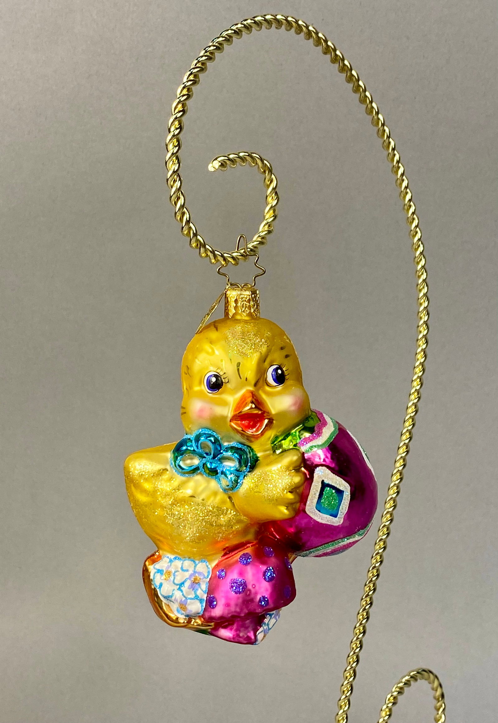 Radko Easter Outing Glass Chick Ornament: Stand Not Included. This is a hand-blown glass ornament manufactured by Christopher Radko, identified as the Easter Outing pattern. The piece depicts a stylized yellow chick wearing a blue glittered b