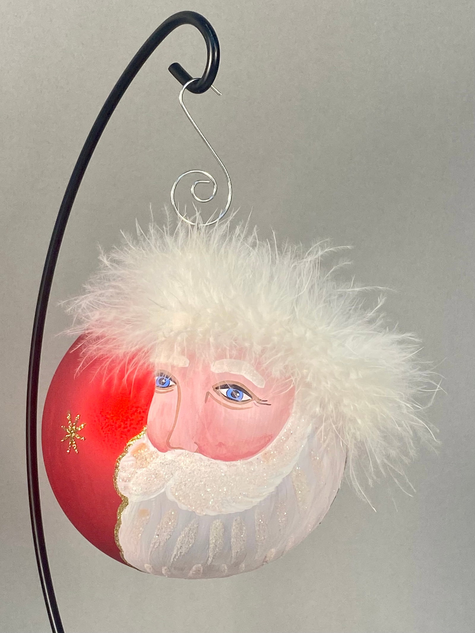 A Hand-Painted German Glass Santa Claus Ornament: Stand Not Included. This hand-painted glass Christmas ball ornament features a detailed depiction of Santa Claus on a red matte-finish ground. The front of the ornament displays Santa's face with