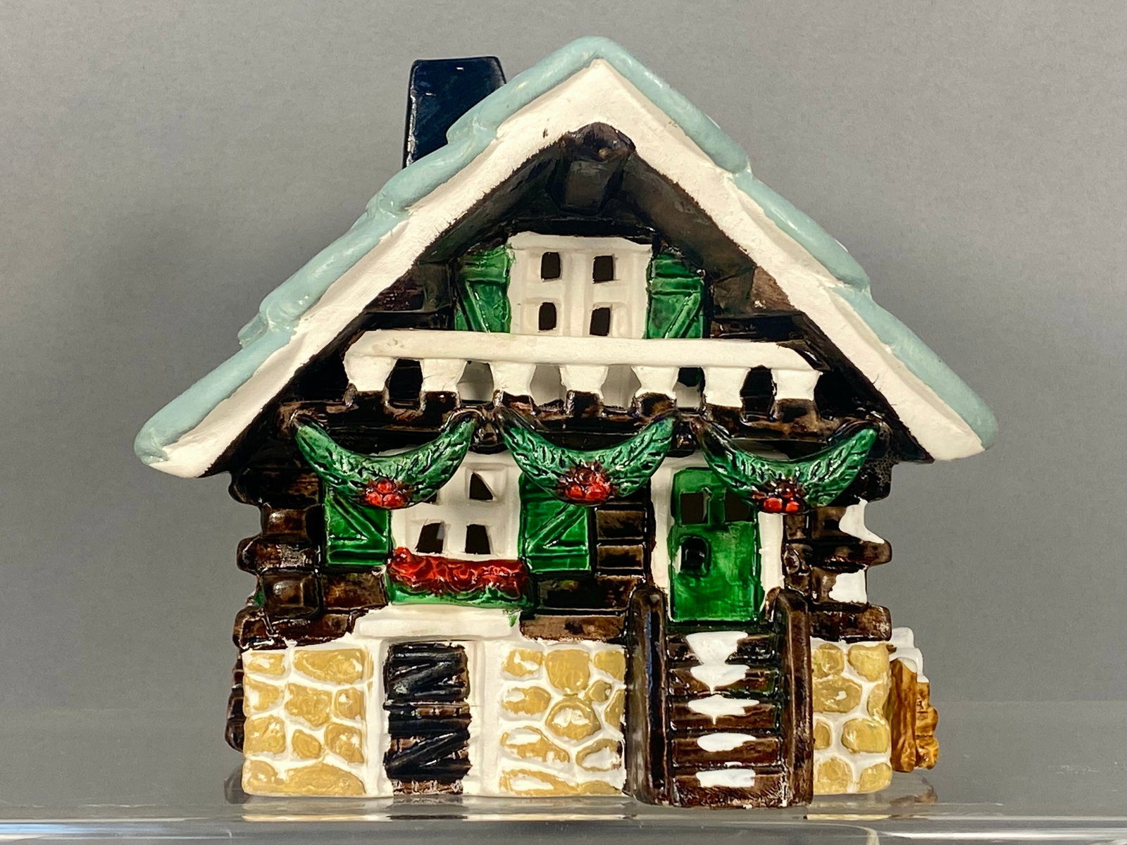 Department 56 Snowhouse Series Swiss Chalet Lighted Ceramic House 1983: This Department 56 Snowhouse Series Swiss Chalet is a hand-painted glazed ceramic decorative building. The piece features a light blue gabled roof with white snow accents, dark brown log-textured wall