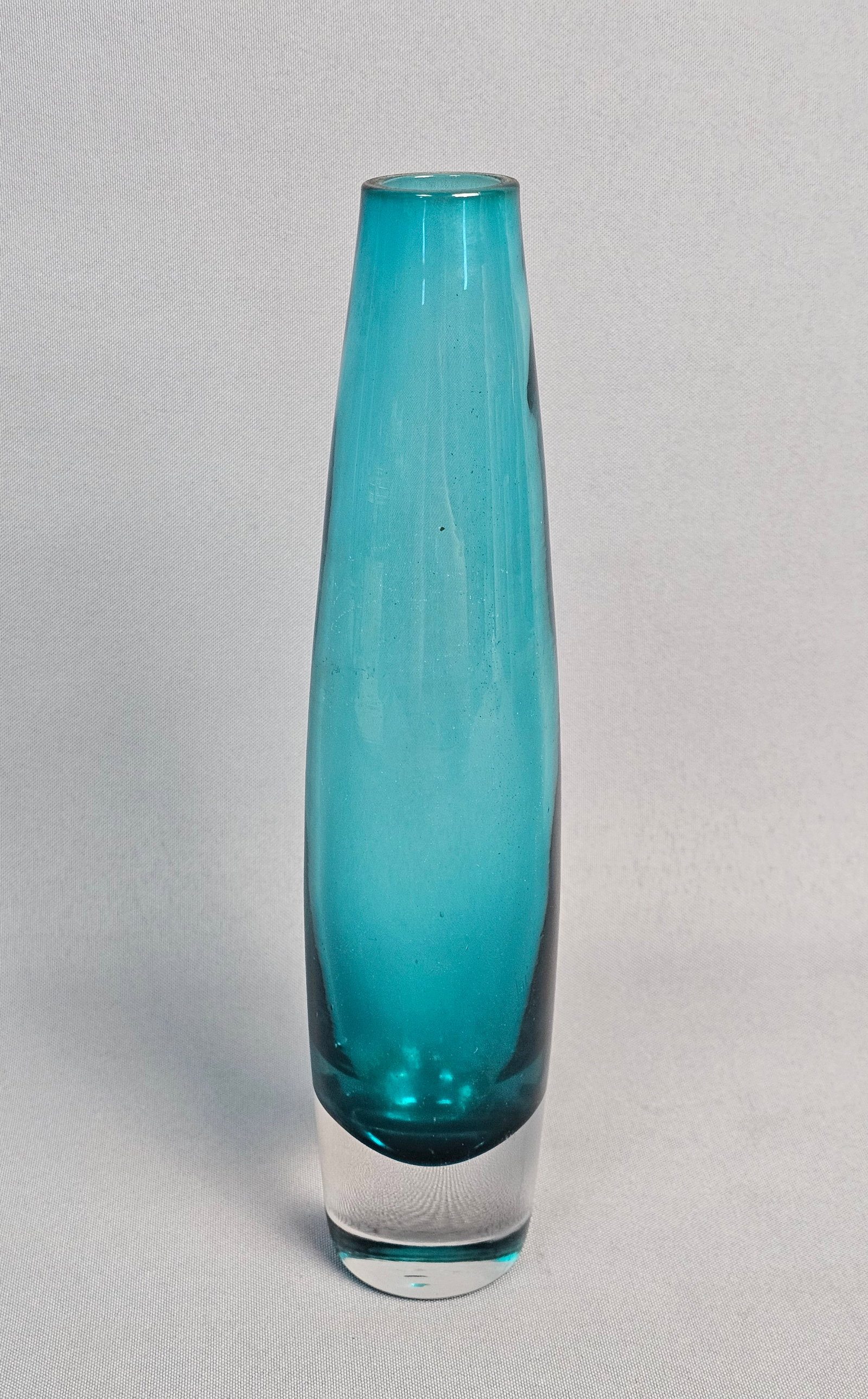Tall Turquoise Sommerso Glass Vase: This mid-century modern art glass vase features a slender, tapered cylindrical form. It is crafted using the sommerso technique, with a vibrant turquoise blue core encased within a thick layer of clea