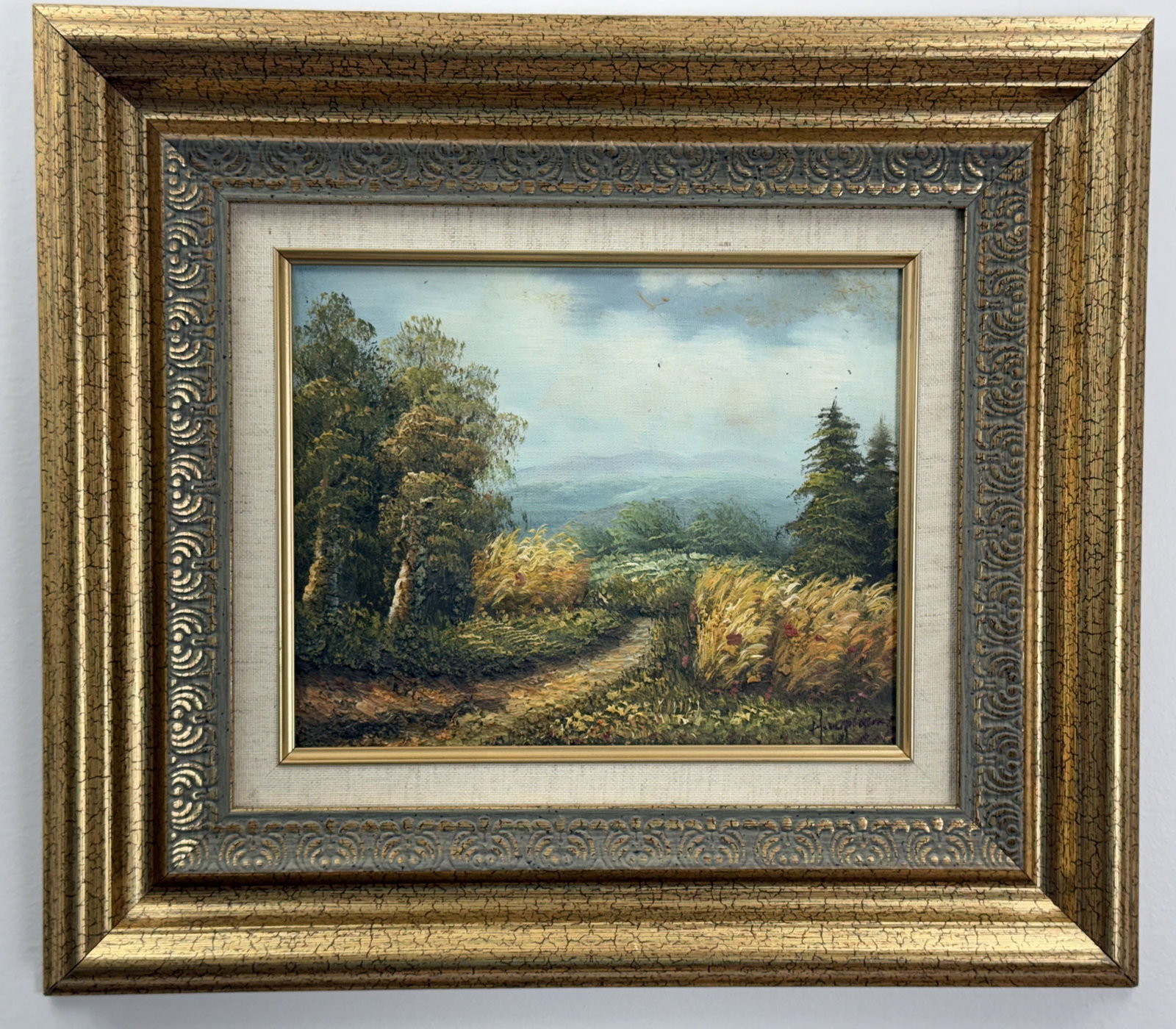 Rural Landscape with Path and Mountains, Oil on Canvas Board: This oil painting on canvas board, signed in the lower right corner, depicts a tranquil rural landscape. The work is housed in an ornate, multi-tiered gilt wood frame featuring a heavily textured "cra