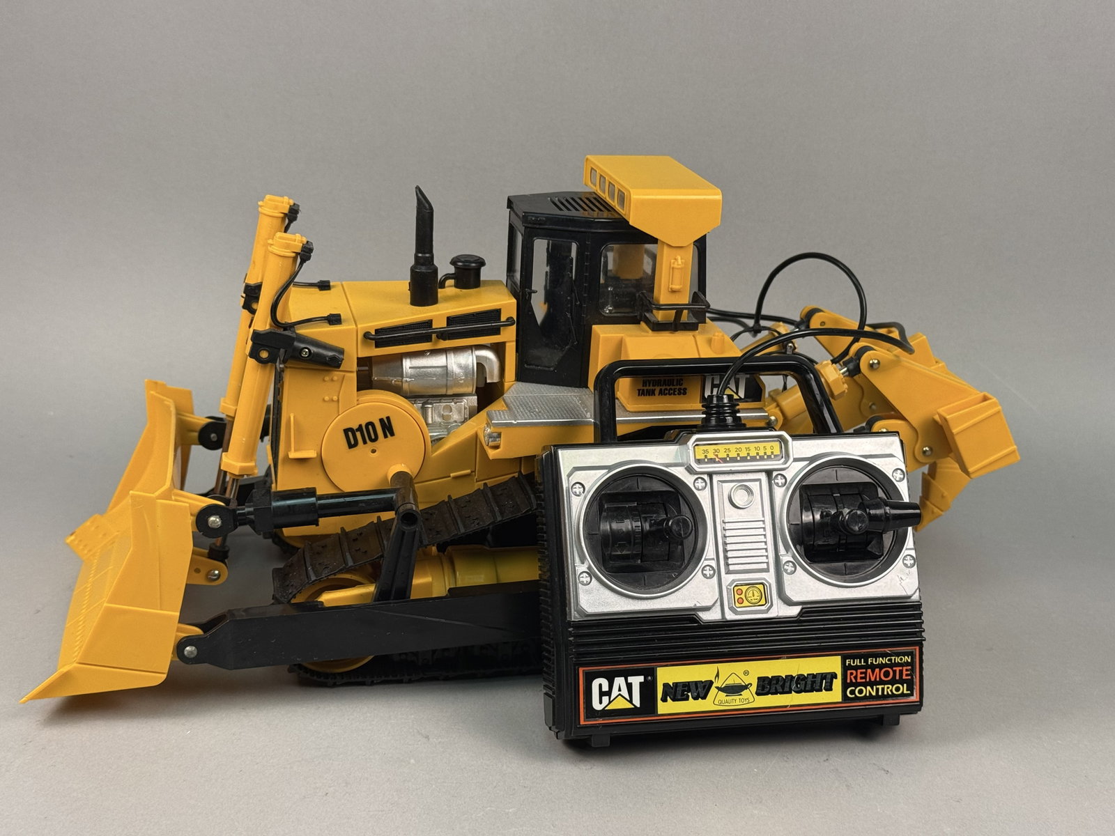 New Bright Caterpillar D10N Tethered Remote Control Bulldozer: This Caterpillar (CAT) D10N model bulldozer was manufactured by New Bright Industrial Co., Ltd. The underside of the bulldozer is embossed with the New Bright bowl and flame logo and reads Â© New Br