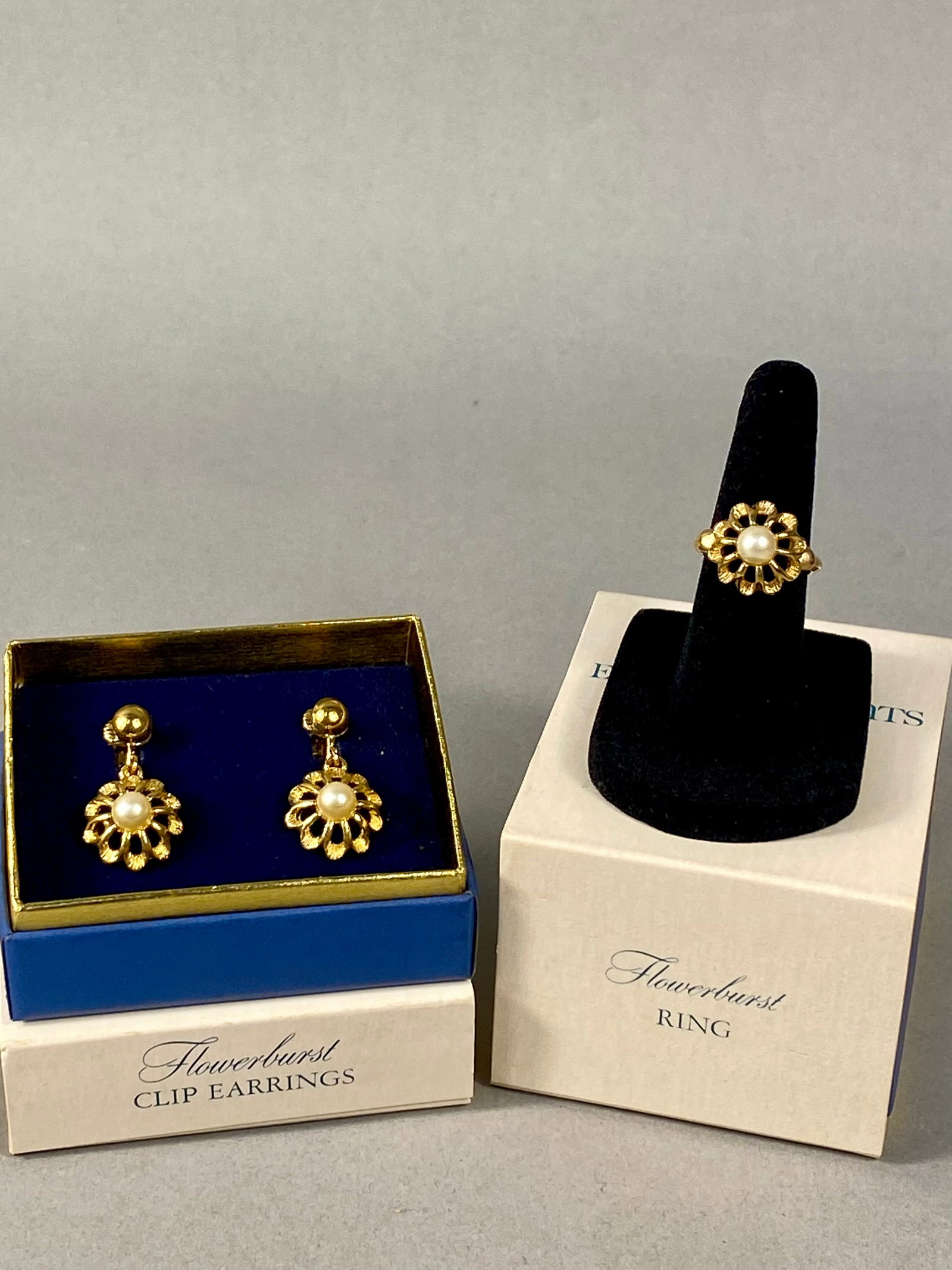 Avon 1974 Flowerburst Earrings & Ring Set: This lot features jewelry from the Avon Flowerburst line, consisting of a pair of clip-on dangle earrings and a coordinating ring. Each piece is crafted in a yellow gold-tone metal and features a text