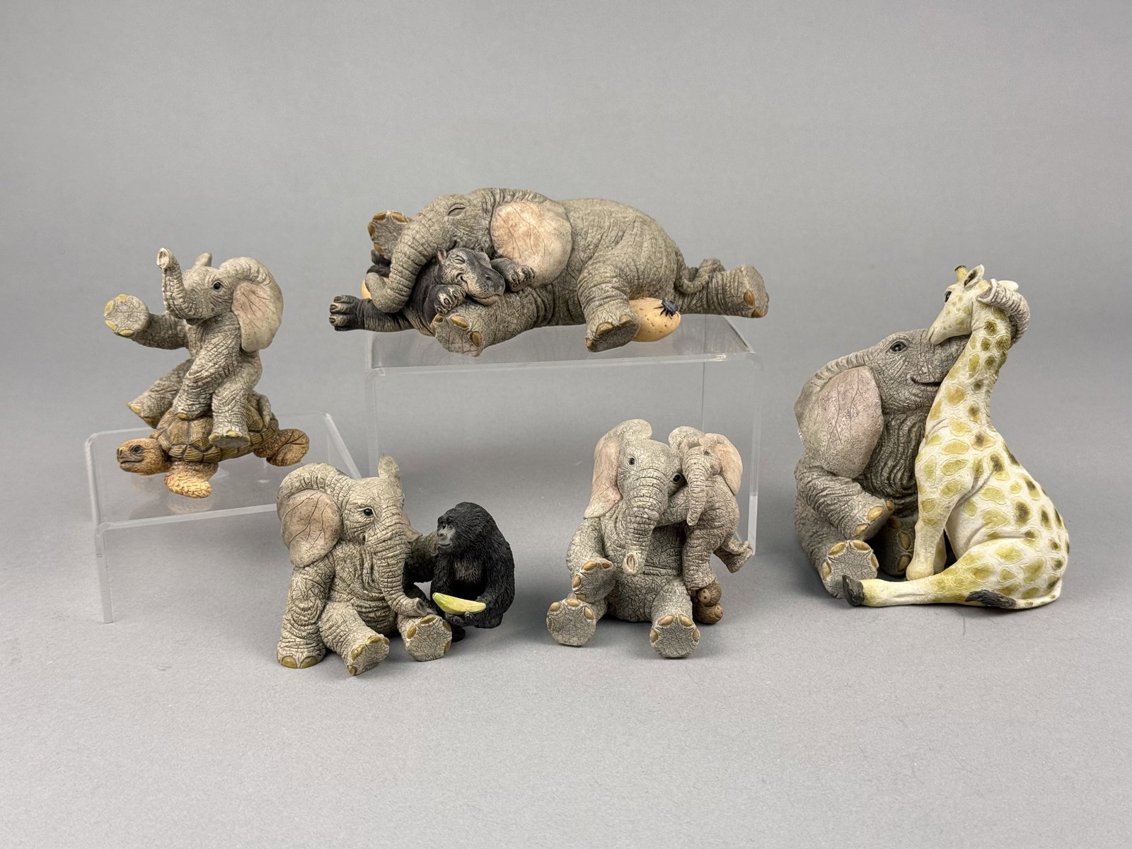 Five Tuskers Elephant Figurines by Barry Price for Enesco: A collection of five Tuskers animal figurines designed by artist Barry Price for Enesco. The collection consists of five distinct designs. Markings include blue printed Tuskers brand marks, model numb