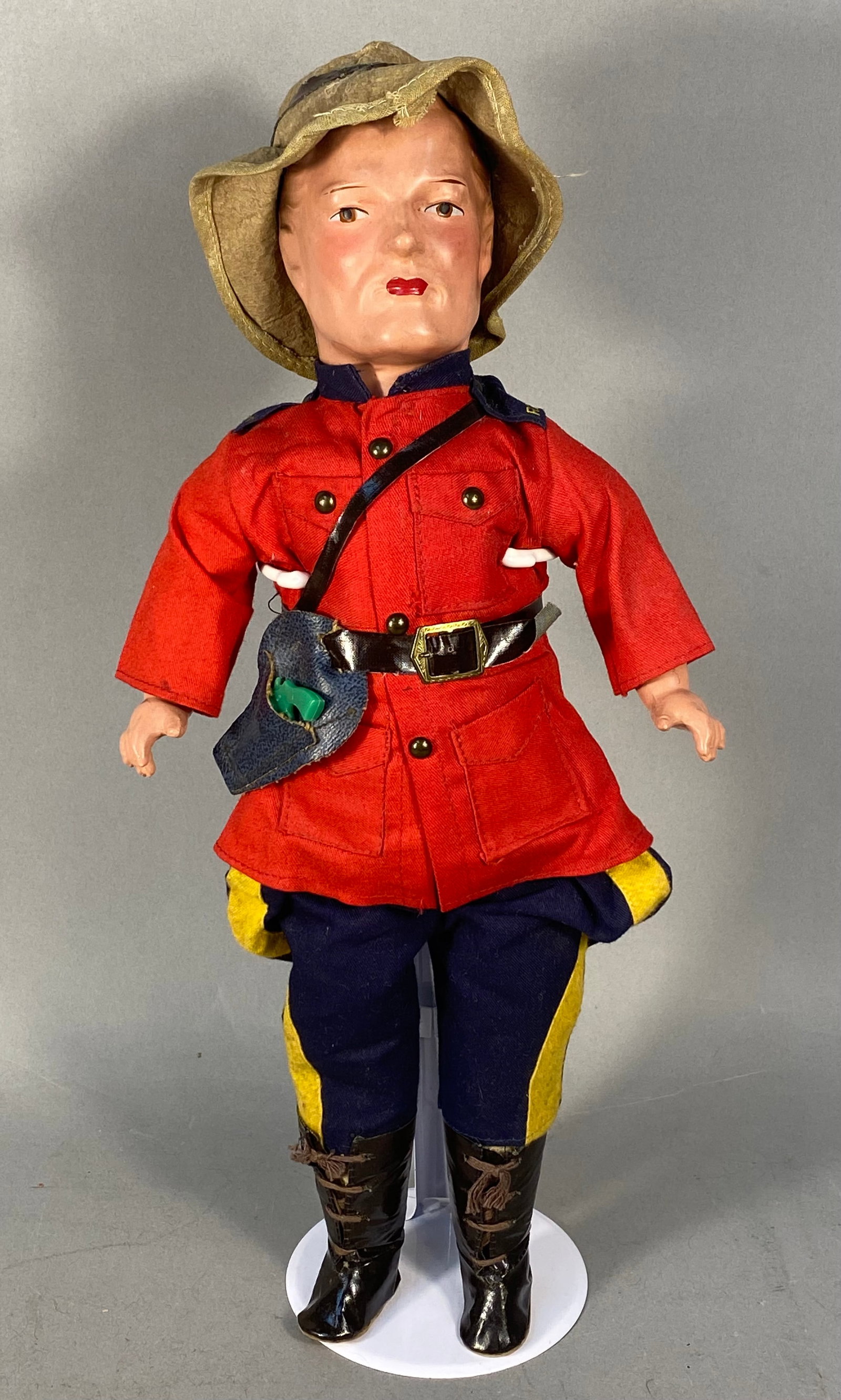 Vintage Reliable Royal Canadian MP Composition & Cloth Doll: A vintage Royal Canadian Mounted Police (RCMP) doll manufactured by the Reliable Toy Company of Canada. The doll features a composition head and hands with a stuffed cloth body. The head has molded an
