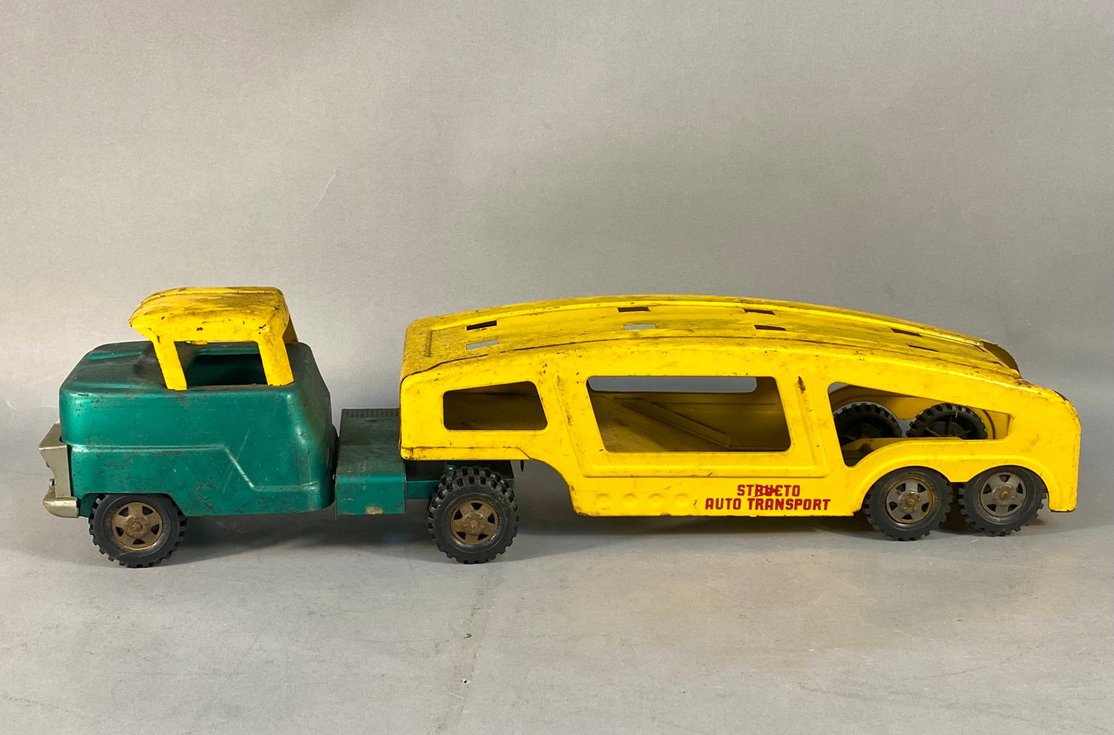 Vintage Structo Toys Auto Transport Tractor and Trailer: A vintage Structo Toys auto transport tractor and trailer set. The car carrier is constructed of pressed steel with a plastic front grille and bumper assembly. The tractor cab is finished in teal gree