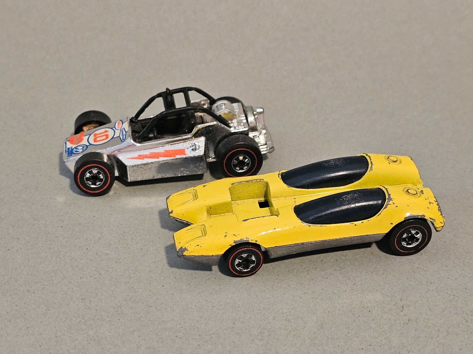 Vintage Hot Wheels Redline Die-Cast Cars: This lot features two vintage Hot Wheels Redline die-cast toy cars manufactured by Mattel. The first car is the Splittin' Image model (1968), characterized by its twin-cockpit design with blue-tinted 