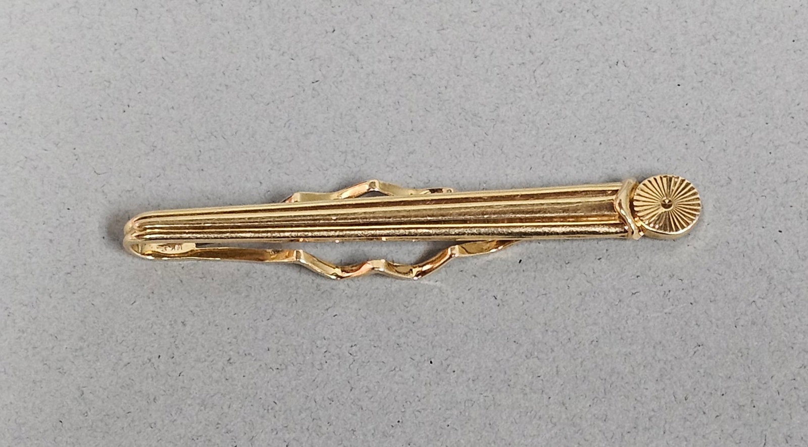 14K Yellow Gold Triple-Ribbed Tie Clip 6.6 Grams: This 14 karat yellow gold tie clip features a triple-ribbed bar design. Length: 2.5 inches Weight: 6.6 grams. The item is in good overall condition with minor surface wear and light scratches consiste