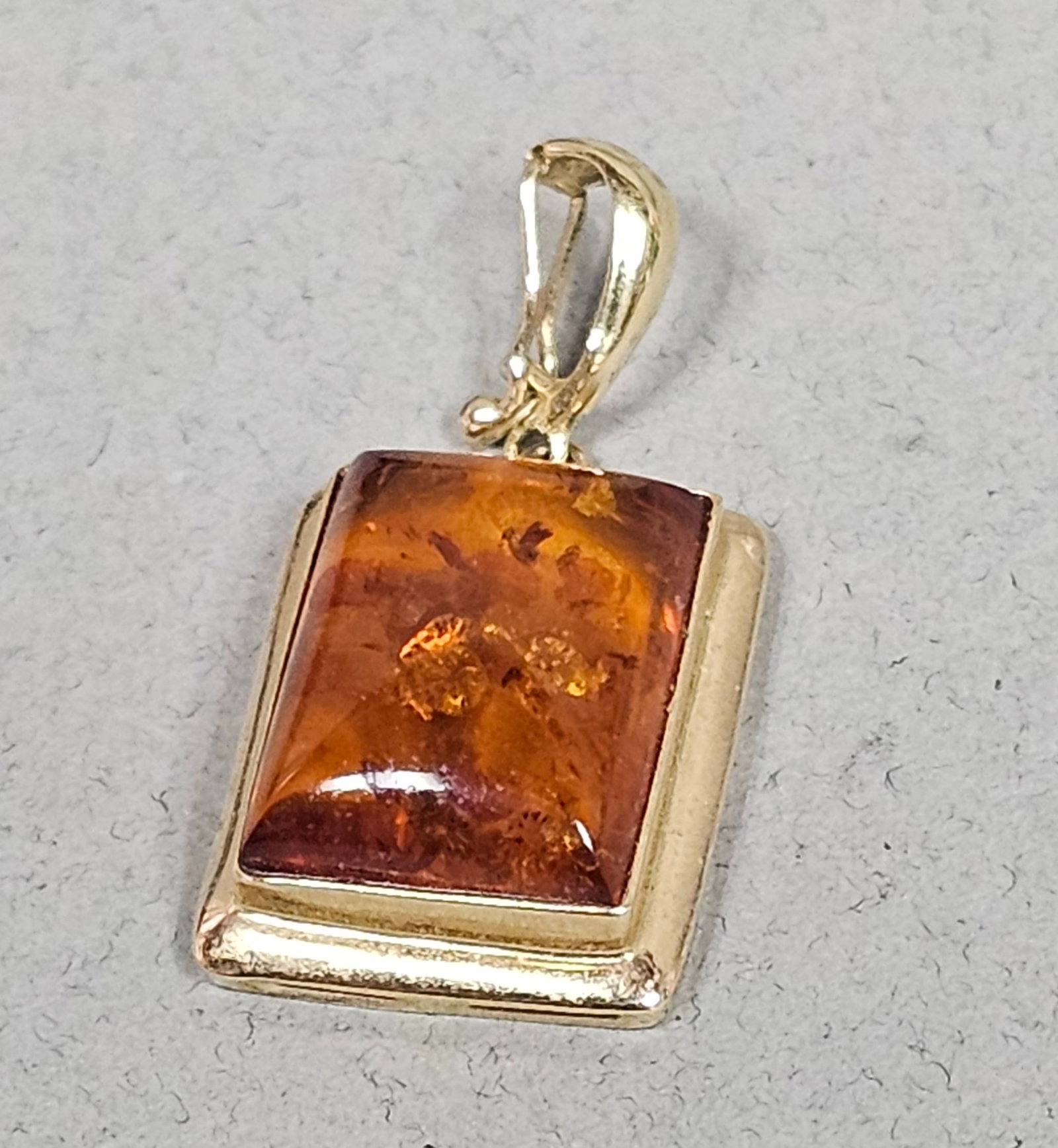 14K Yellow Gold Amber Pendant 1.9 Grams: The main rectangular body of the pendant measures approximately 5/8 inch long by 3/8 inch wide. The total length including the bail is approximately 7/8 inch. Weight: Approximately 1.9 grams total. Th