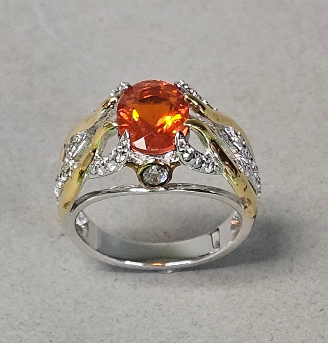Sterling Orange Gemstone Ring 4.6 Grams: A cocktail ring constructed in sterling silver. The piece features a central oval-cut faceted orange gemstone secured in a multi-prong setting. Size: 6 Weight: 4.6 grams. The ring is in good pre-owned