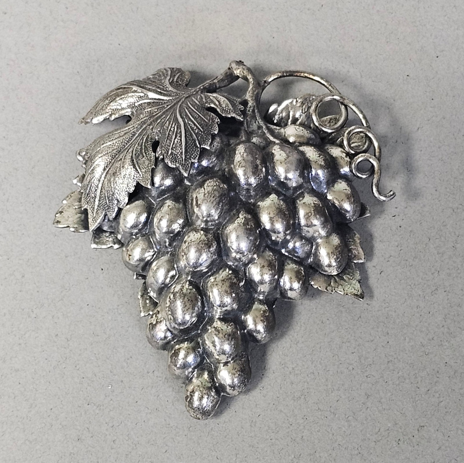 Vintage Napier Silver PLated Grape Cluster Brooch: A vintage costume jewelry brooch by Napier featuring a naturalistic grape cluster motif. The piece is cast in silver plated metal with a heavy oxidized finish that provides depth to the